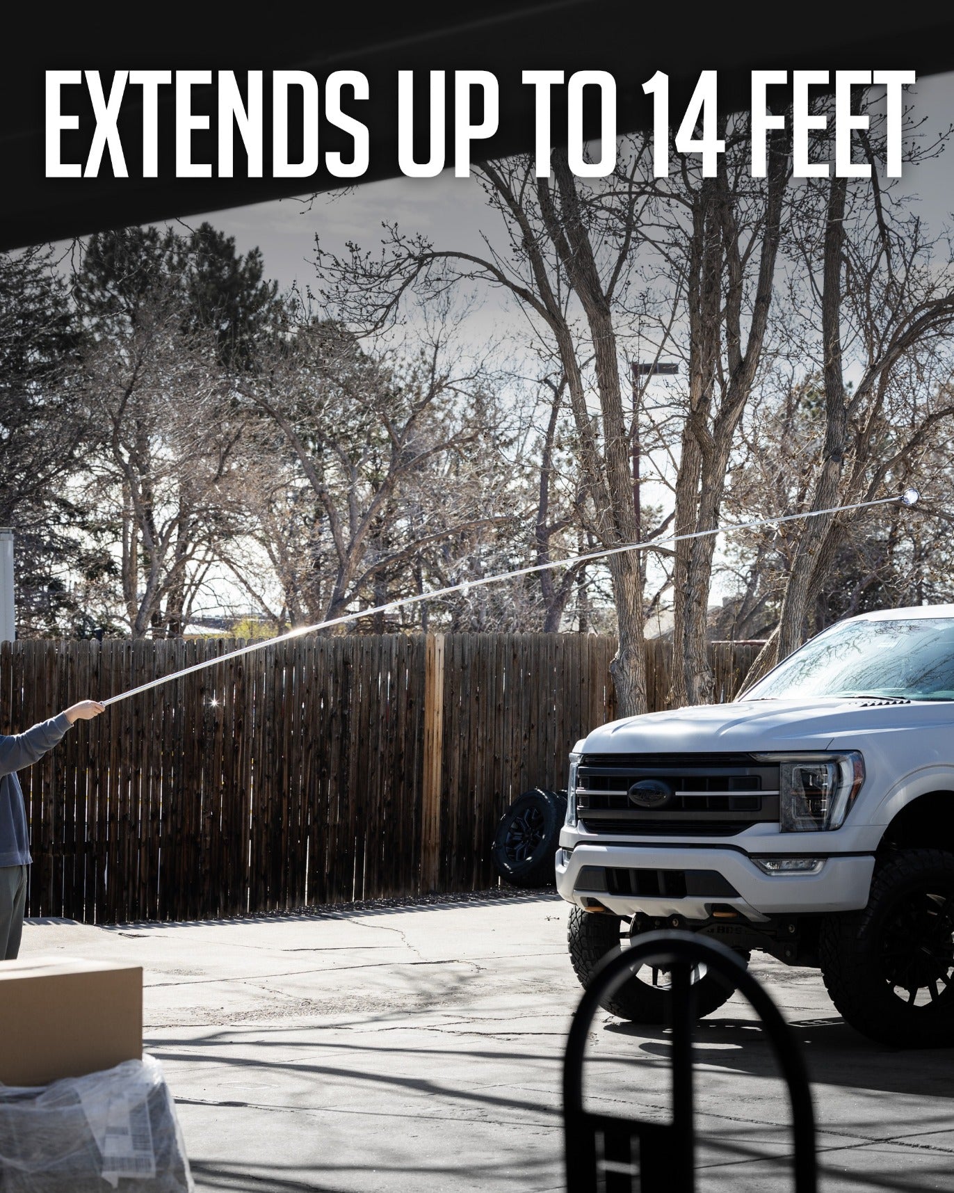 14' ball retriever in use, extending to reach high areas, with a truck and trees in the background.