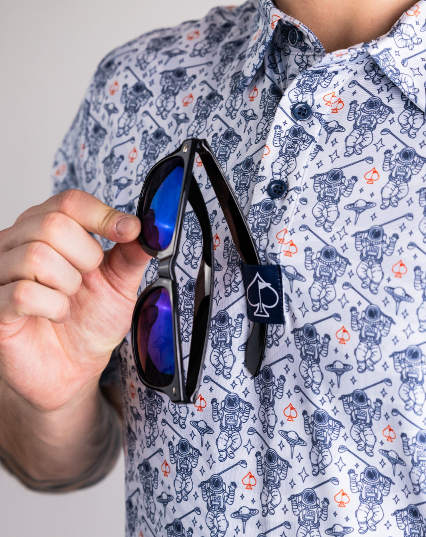 Gray NASA Space Walker shirt featuring astronaut graphics, with a person holding sunglasses in front of it.