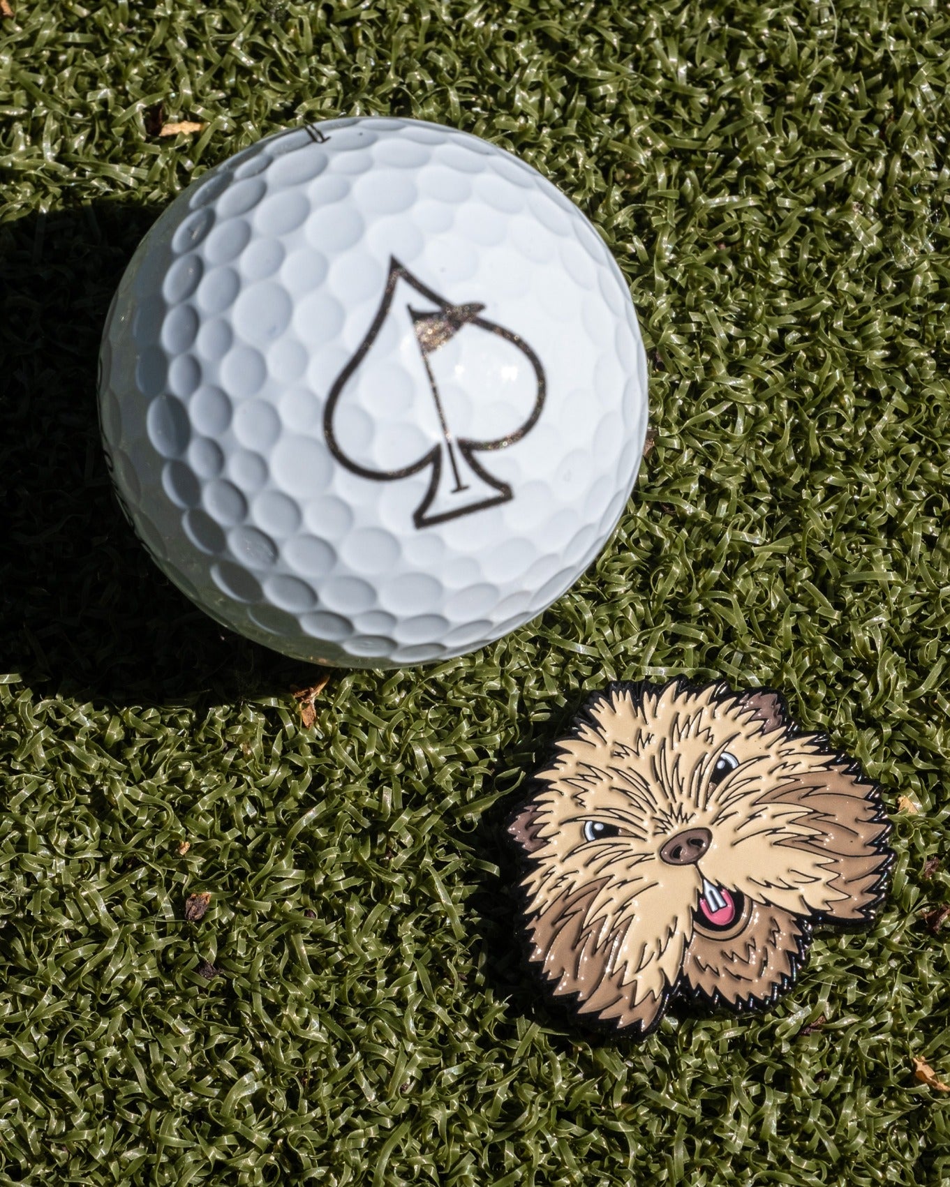 Gopher 2.0 Ball Marker featuring a cute gopher design next to a golf ball with an ace of spades logo on a green surface.