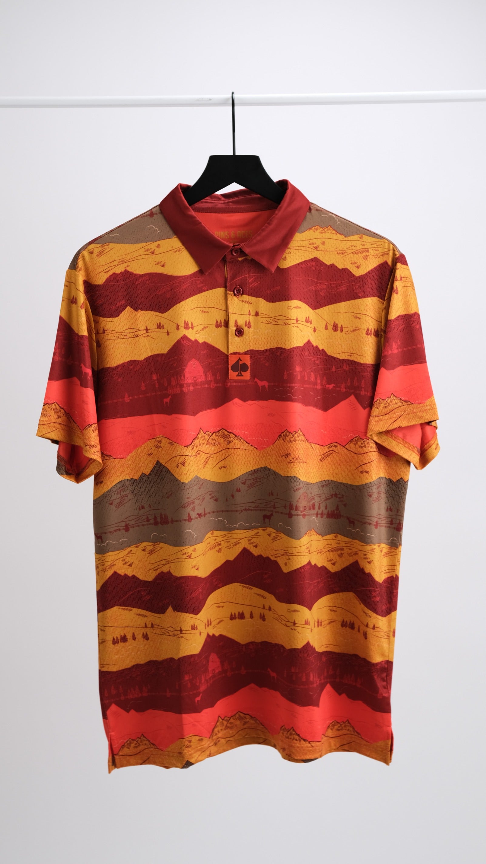 Bold golf polo featuring a vibrant Yellowstone Montana sunset design with layered red and gold mountain stripes.