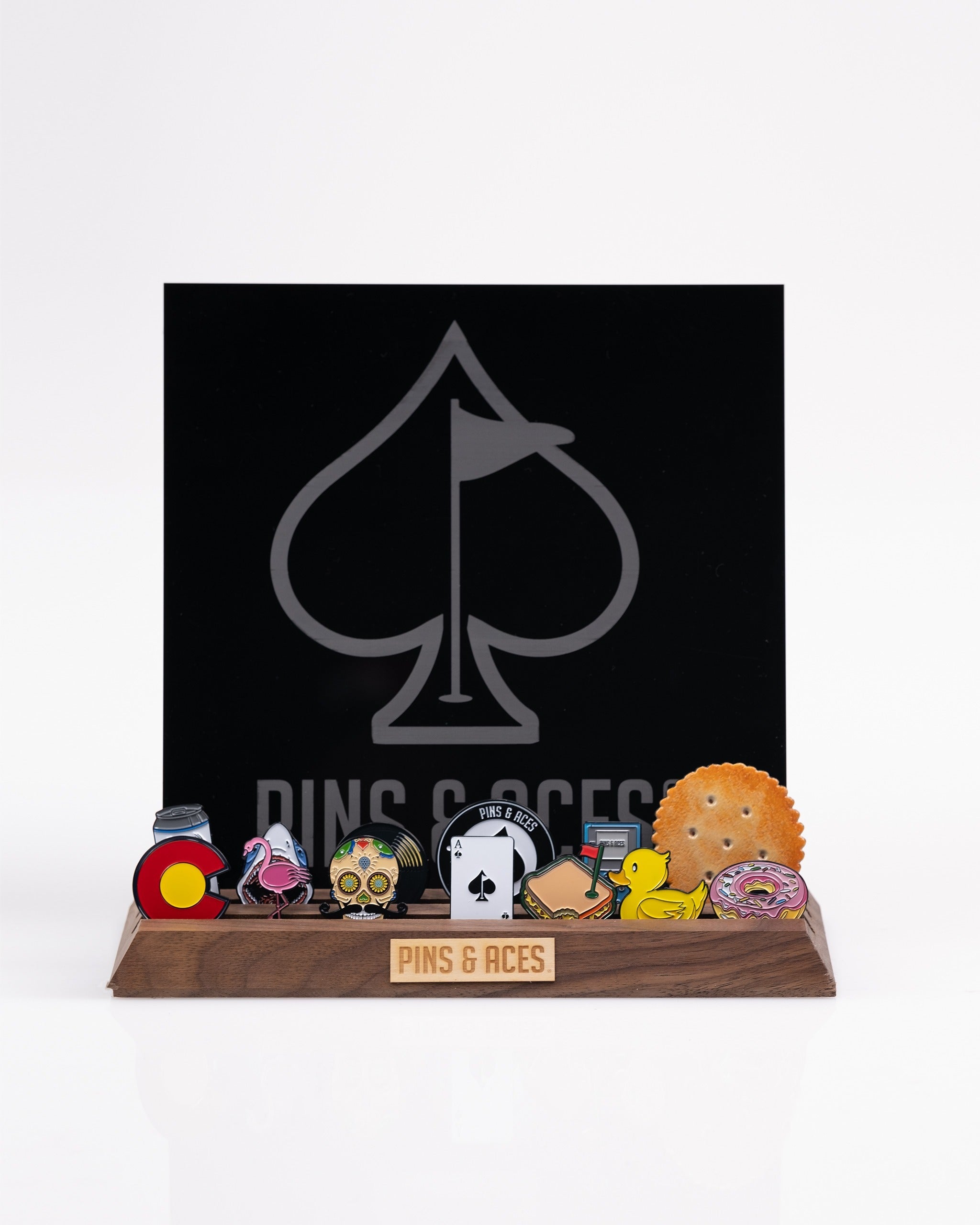 Wooden ball marker display featuring various colorful markers and a sleek black backdrop with the Pins and Aces logo.