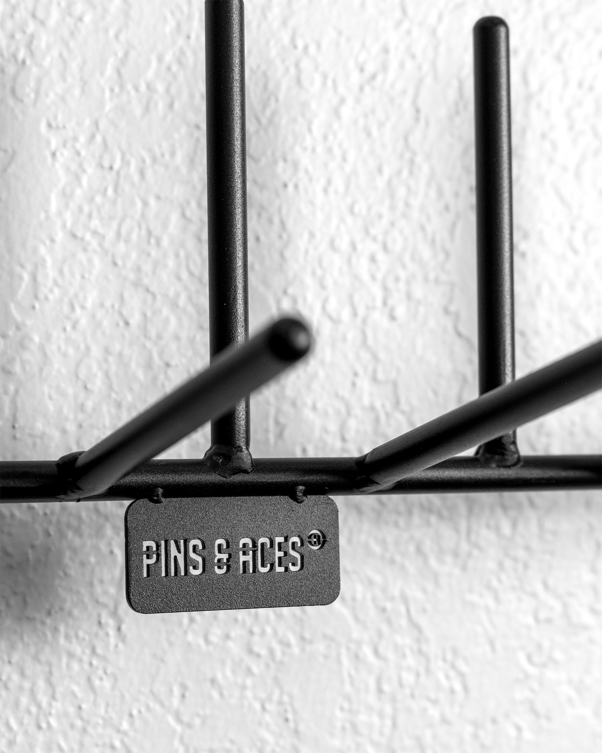 Stylish black headcover rack with multiple hooks and a Pins & Aces logo, perfect for organizing golf accessories.