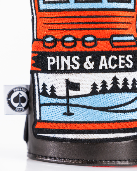 Bold fairway cover featuring a colorful slot machine design, showcasing the Pins & Aces logo and scenic golf elements.