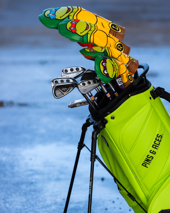 Colorful TMNT Raphael hybrid cover peeking from a bright green golf bag, showcasing unique golf accessories for fans.