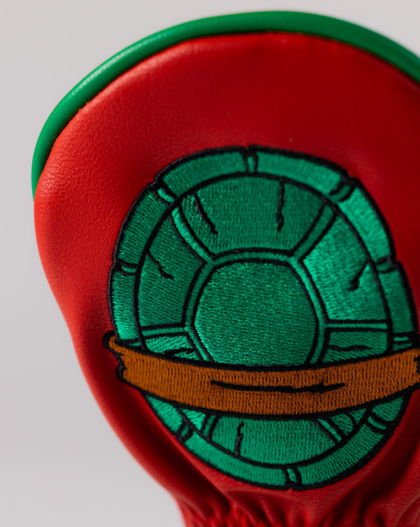 TMNT Raphael hybrid golf cover featuring a vibrant red design with an embroidered turtle shell and brown band.
