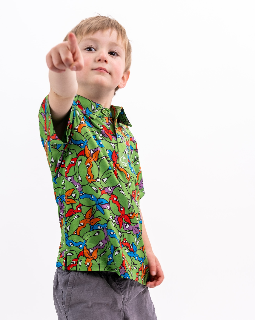 Youth shirt featuring a vibrant Teenage Mutant Ninja Turtles design with colorful characters on a green background.