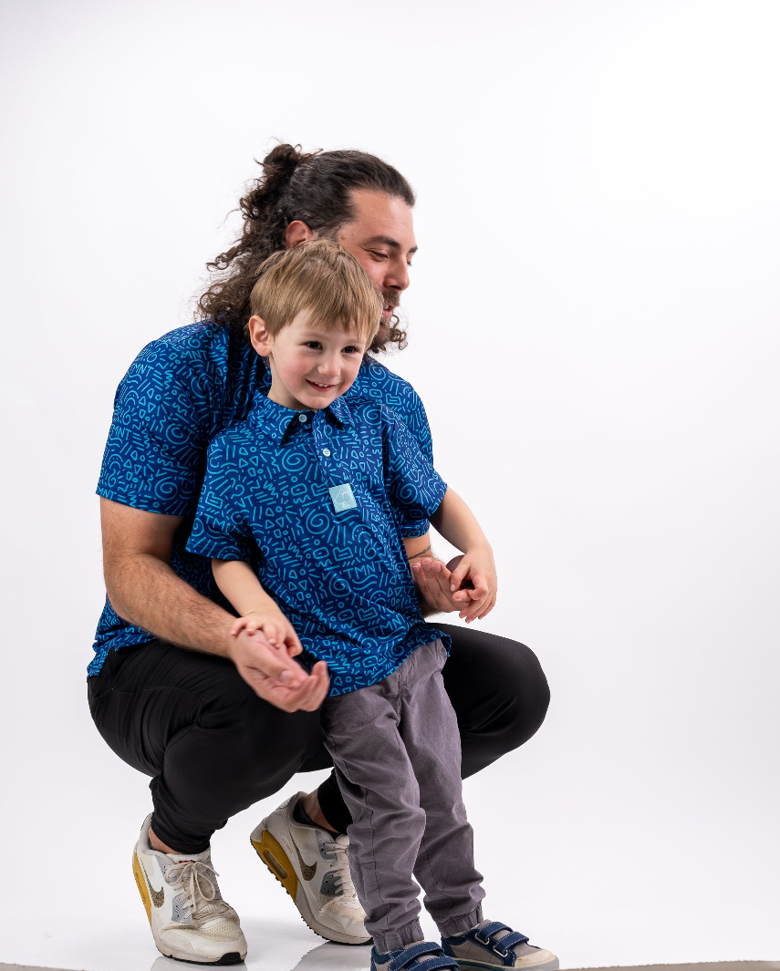 A child wearing a blue TMNT-themed doodle shirt smiles while being held by an adult in a matching shirt.