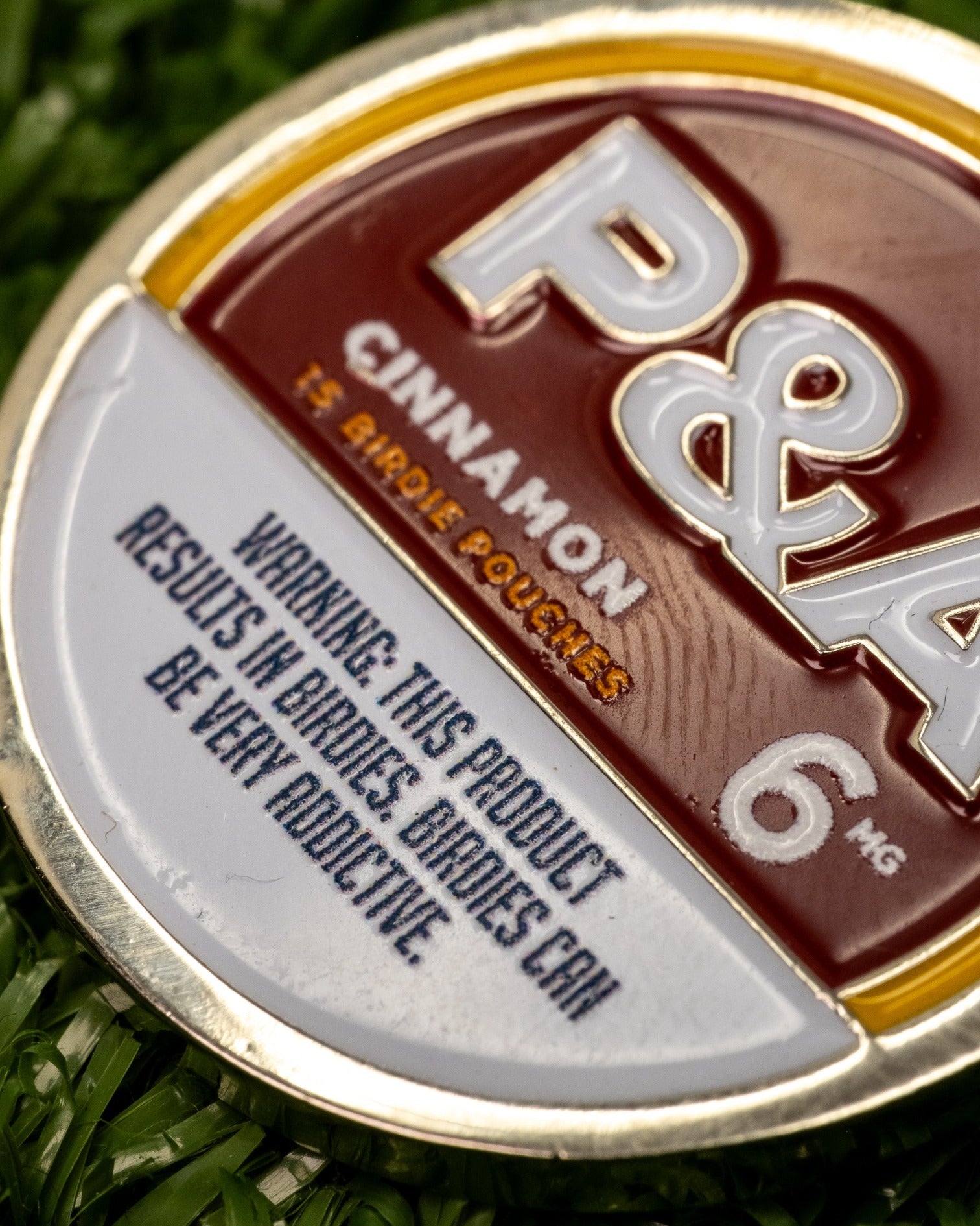Cinnamon ball marker featuring bold design and warning text about addictive nature, perfect for stylish golfers.