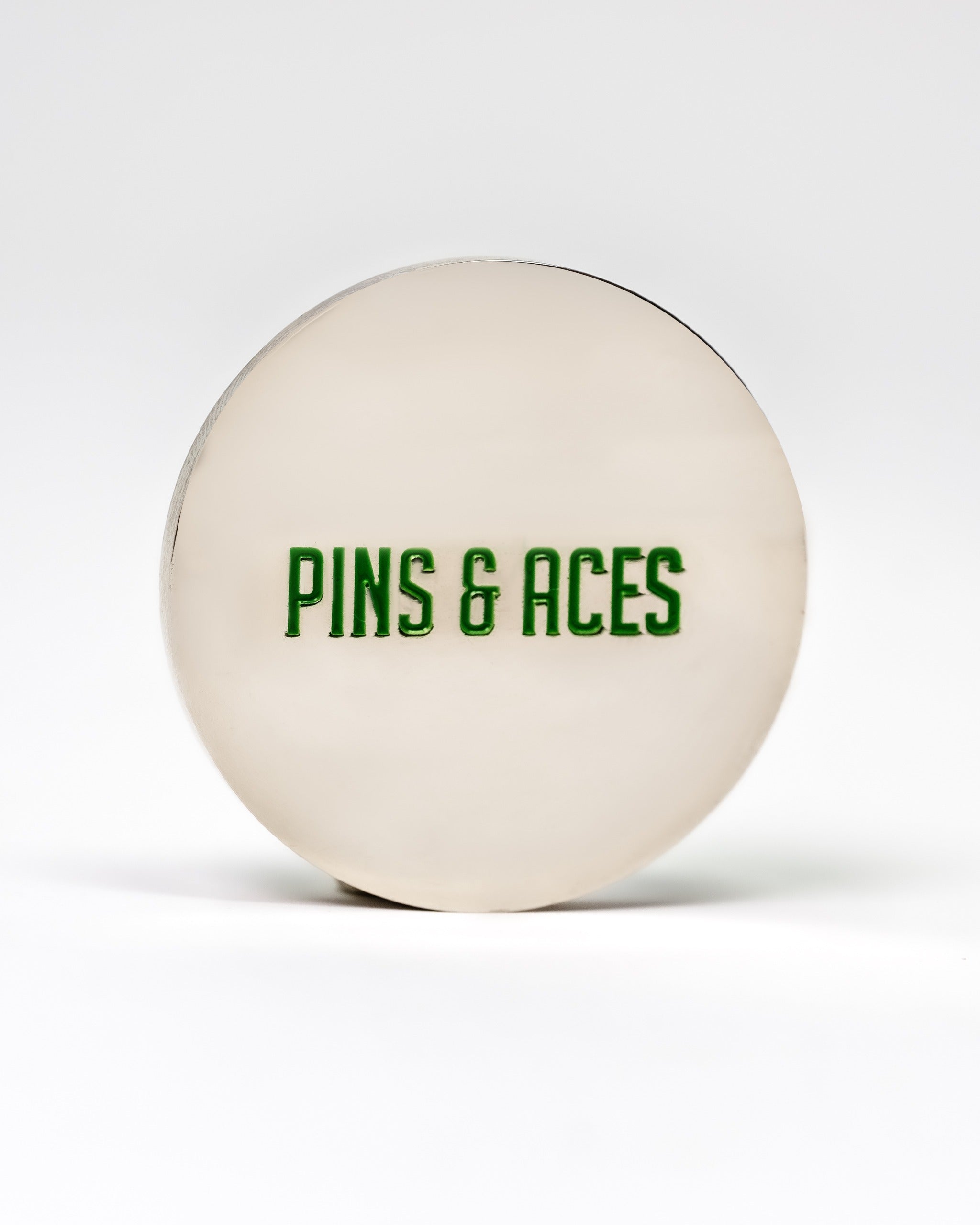 Spearmint ball marker featuring a sleek design with "PINS & ACES" in bold green lettering, perfect for stylish golfers.