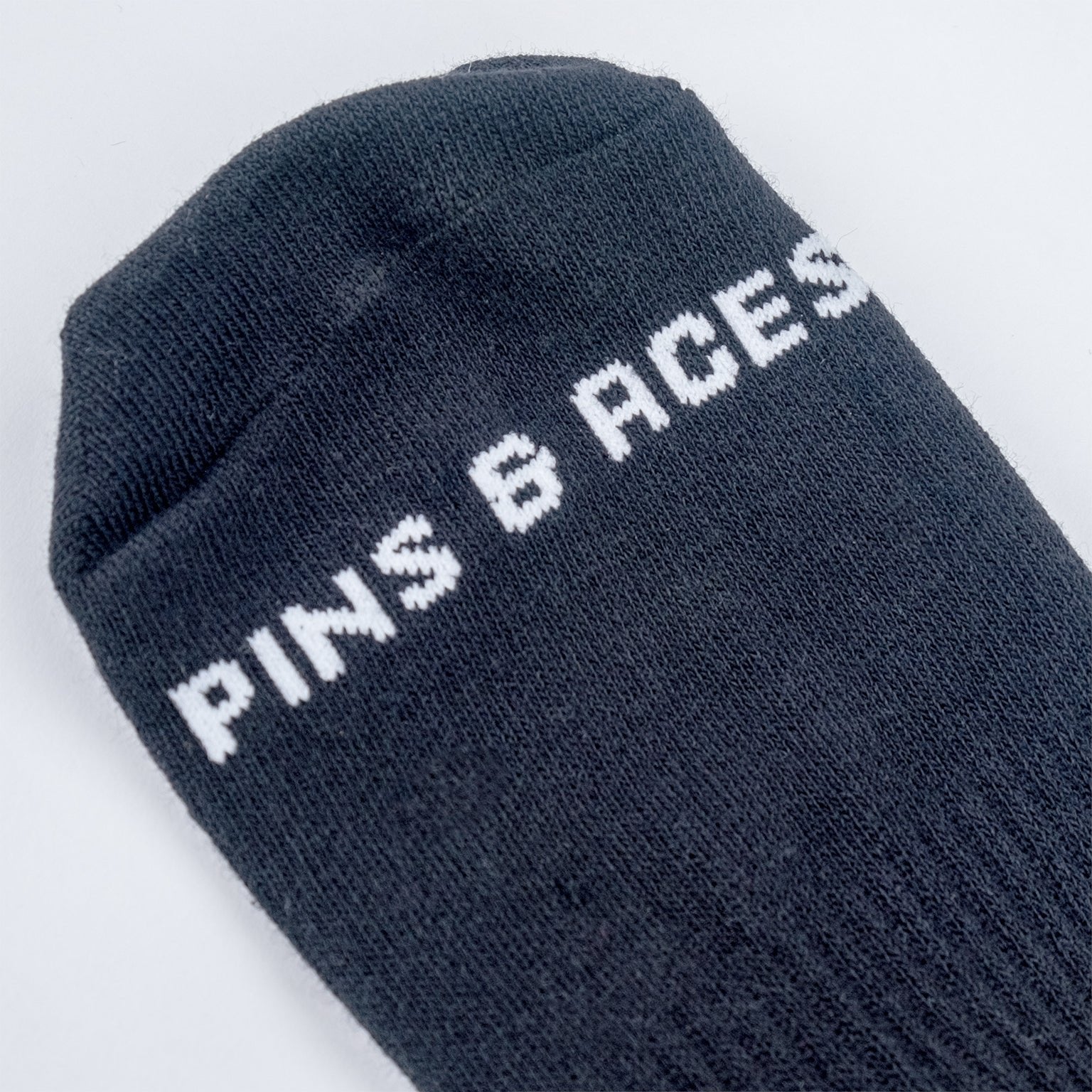 Gray ankle socks featuring "PINS & ACES" logo, designed for golfers seeking stylish and comfortable footwear.