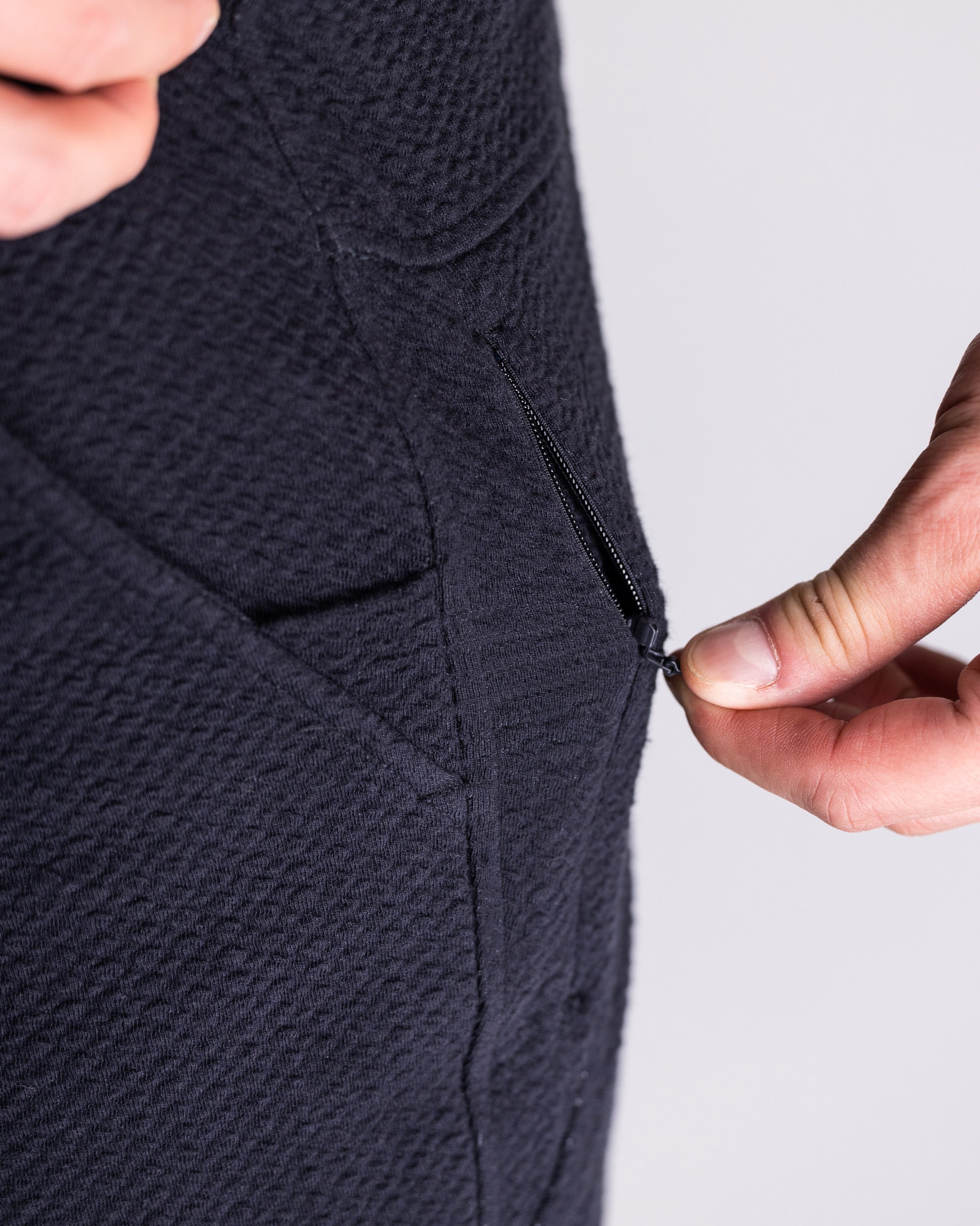 Close-up of a hand zipping the pocket of the Player Preferred Waffleknit Jogger in Obsidian, showcasing its stylish design.