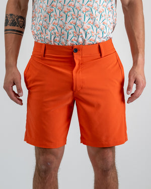Men's performance shorts in vibrant melon color, featuring a tailored fit and stylish pockets, perfect for golf outings.