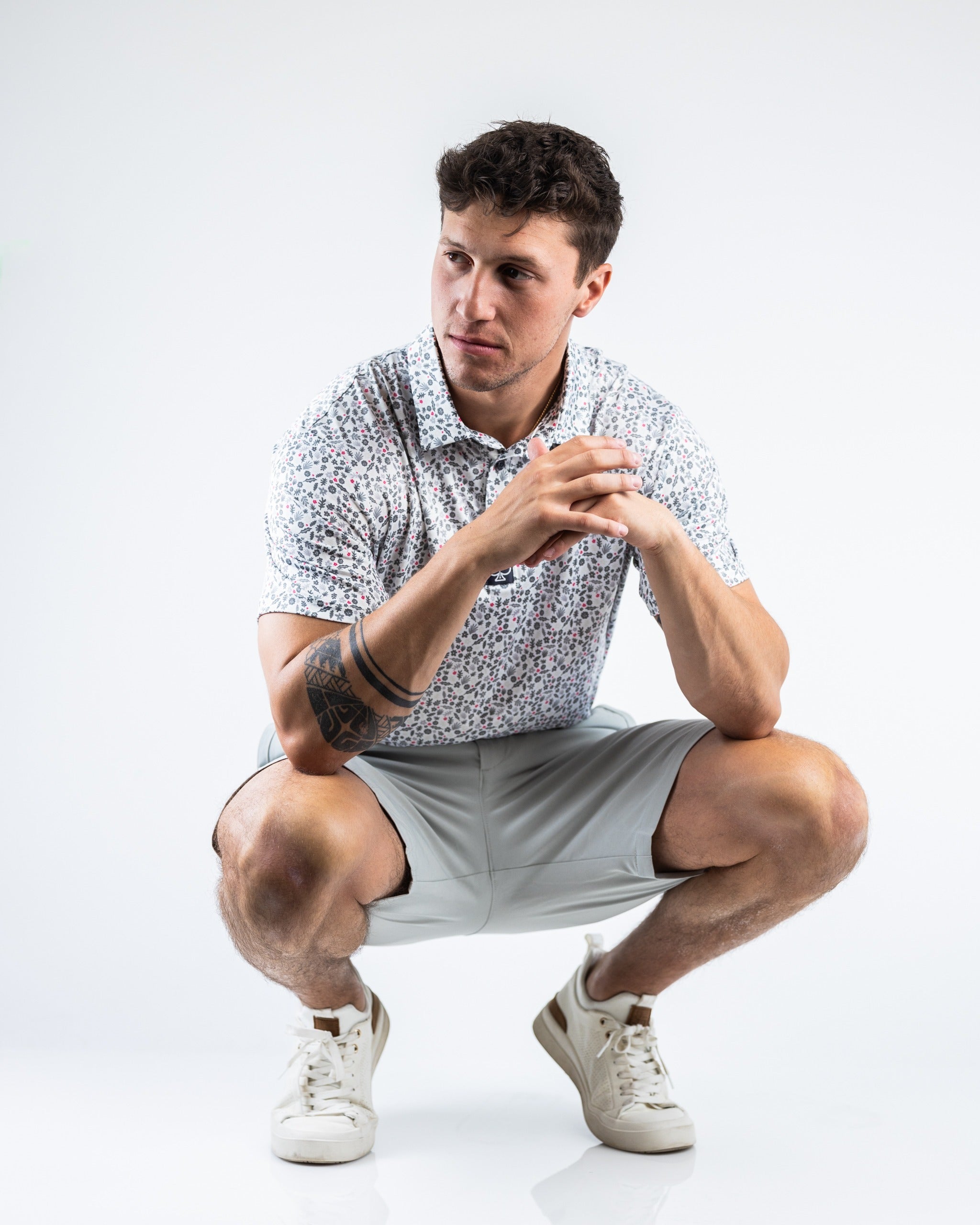 Model wearing dark stone performance shorts paired with a floral shirt, showcasing a stylish and athletic look.