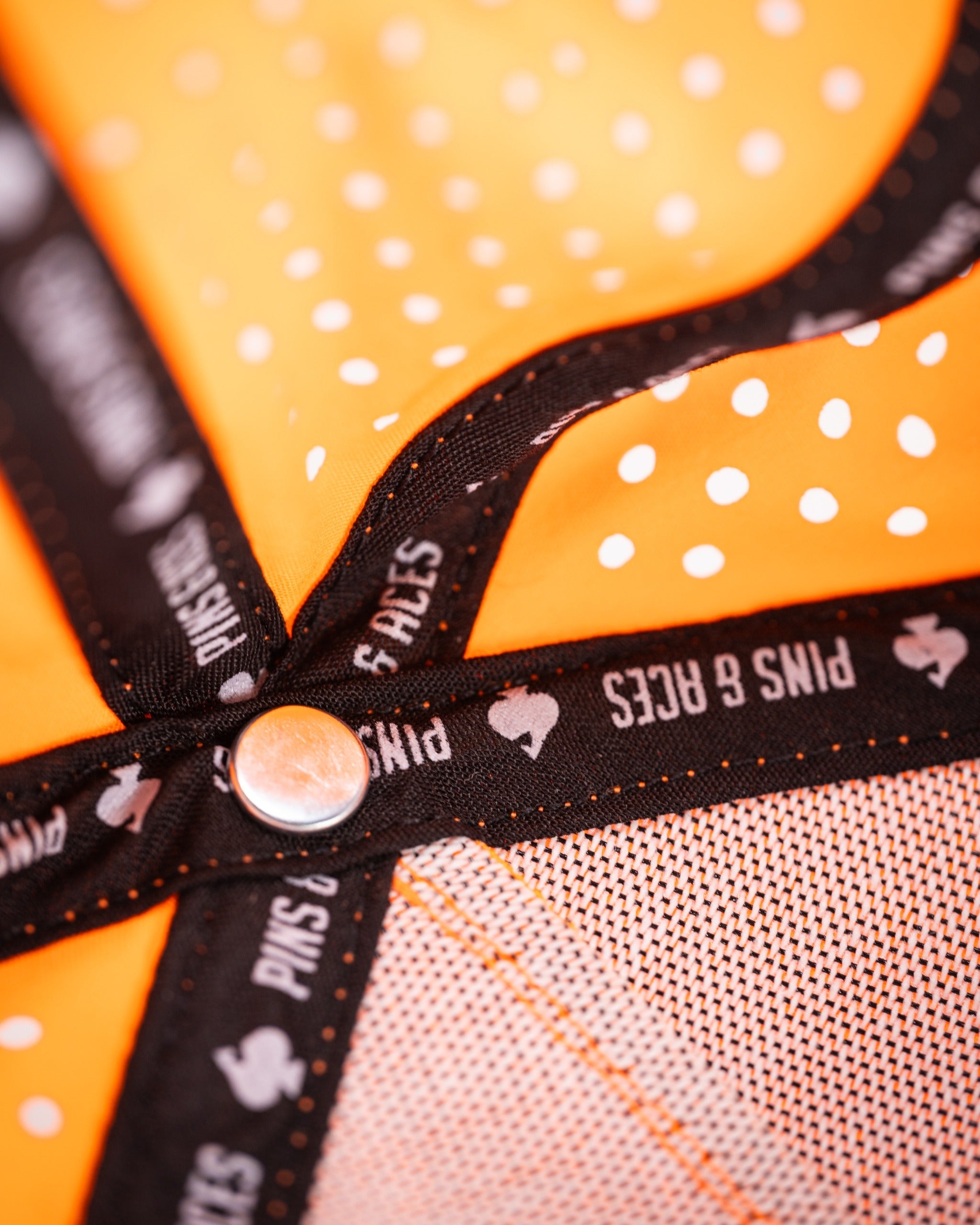 Perforated rope hat in highlighter orange featuring a polka dot design and branded interior lining for golfers.