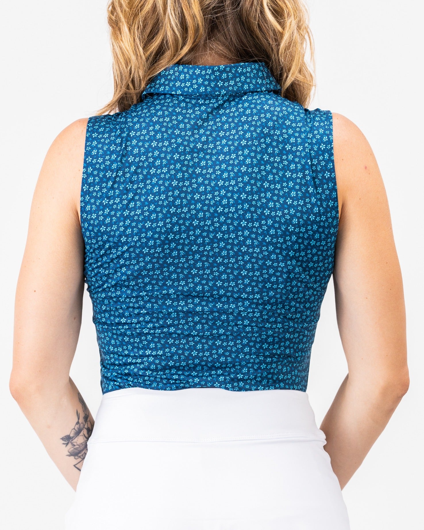 Women's blue micro floral golf top featuring a sleeveless design and a stylish collar, perfect for a bold look on the course.