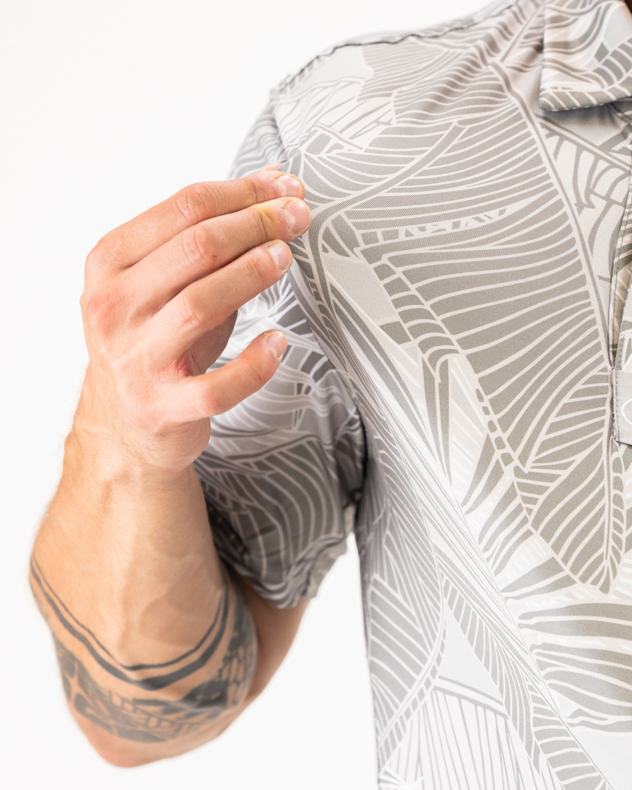 Men's golf shirt featuring a stylish palm leaf pattern in muted tones, perfect for a bold look on the course.