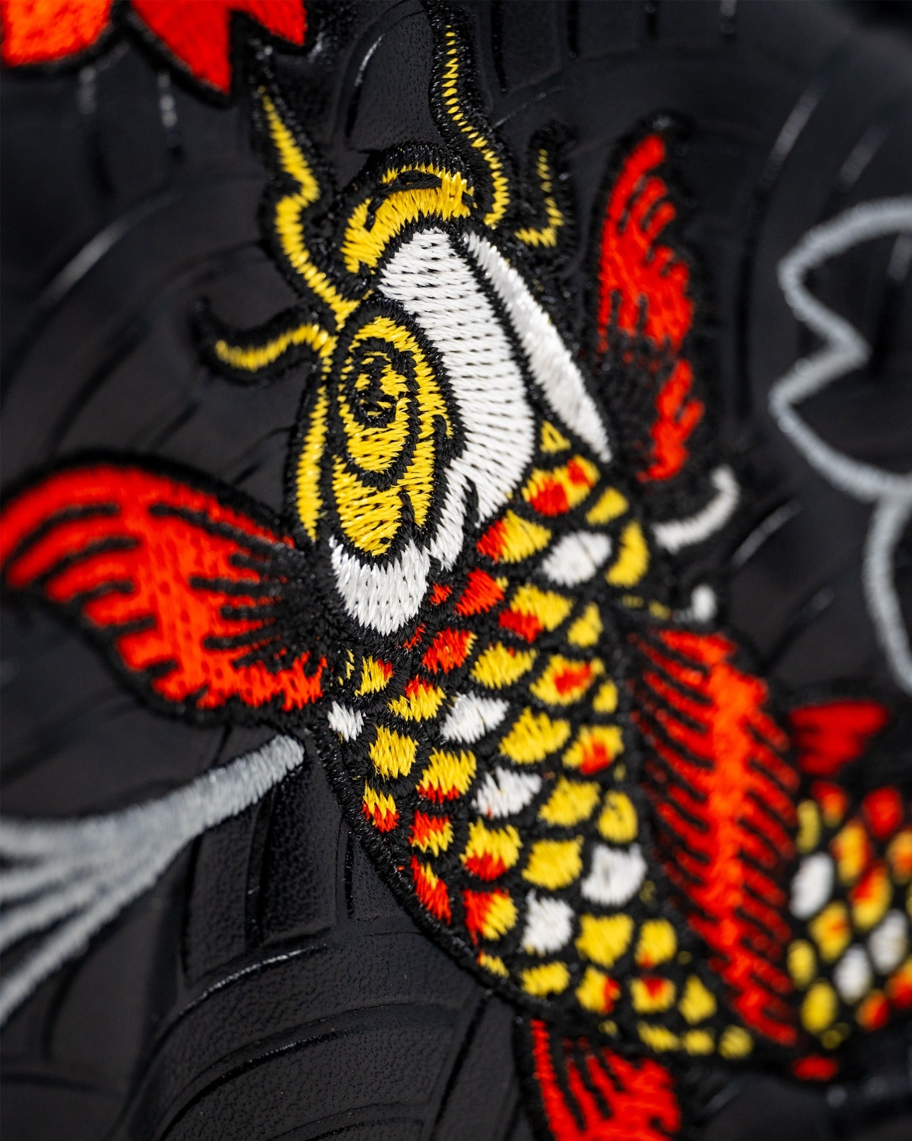 Detailed embroidery of a koi fish in vibrant colors on a black blade putter cover, showcasing unique golf accessory design.