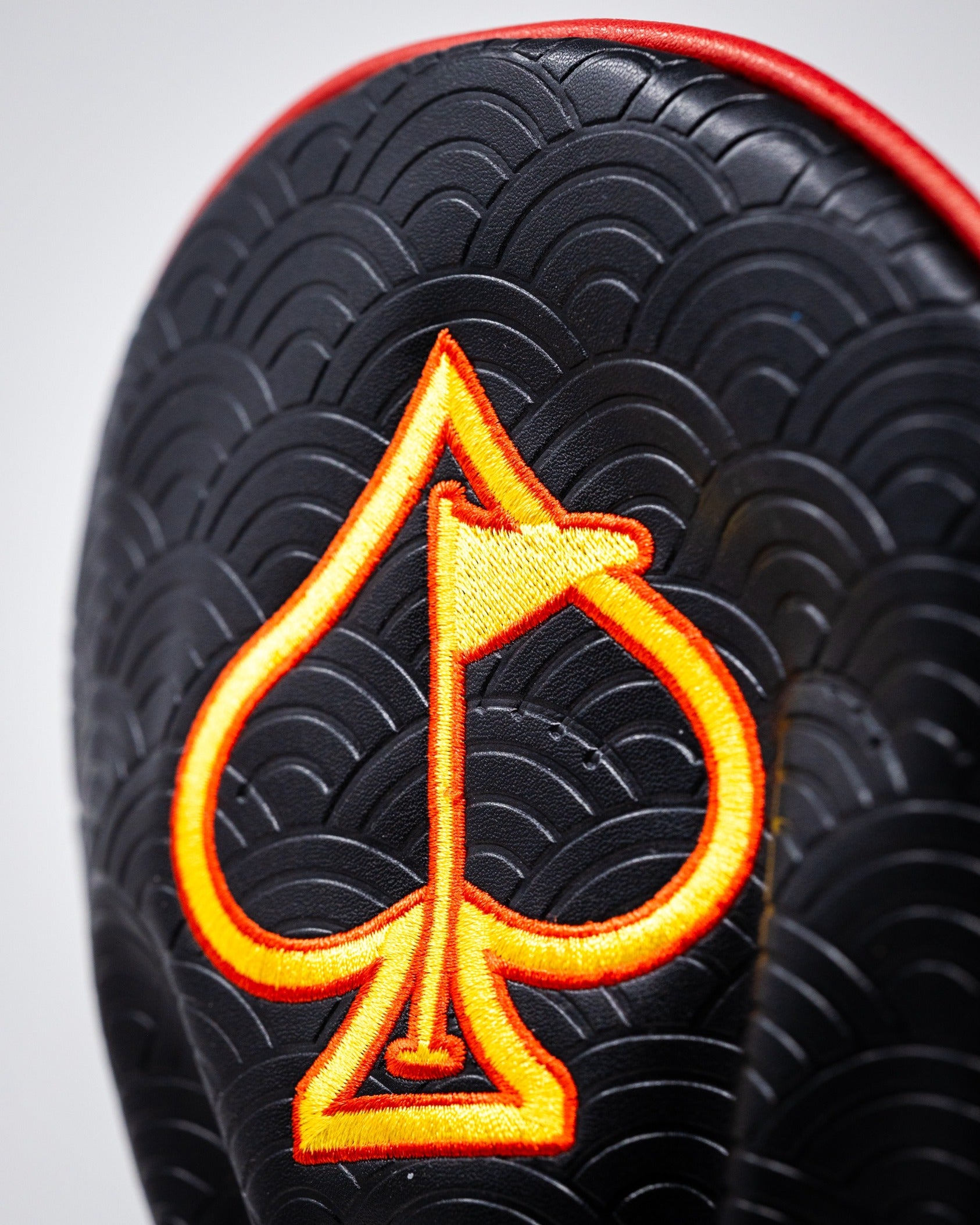 Bold black driver cover featuring a vibrant orange spade design, perfect for golfers wanting to make a statement on the course.
