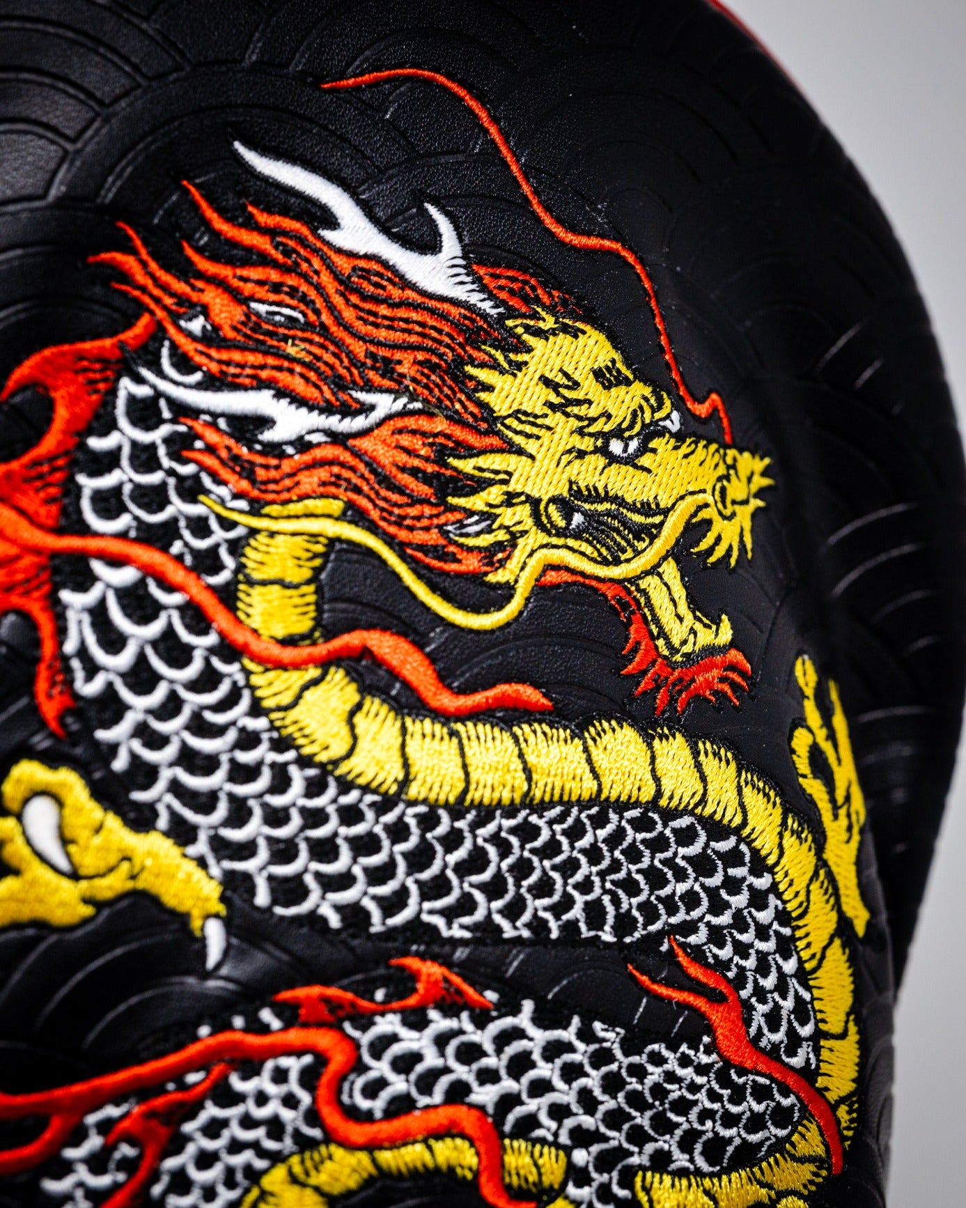Bold black driver cover featuring a vibrant embroidered dragon design in red, yellow, and white, perfect for standout golfers.