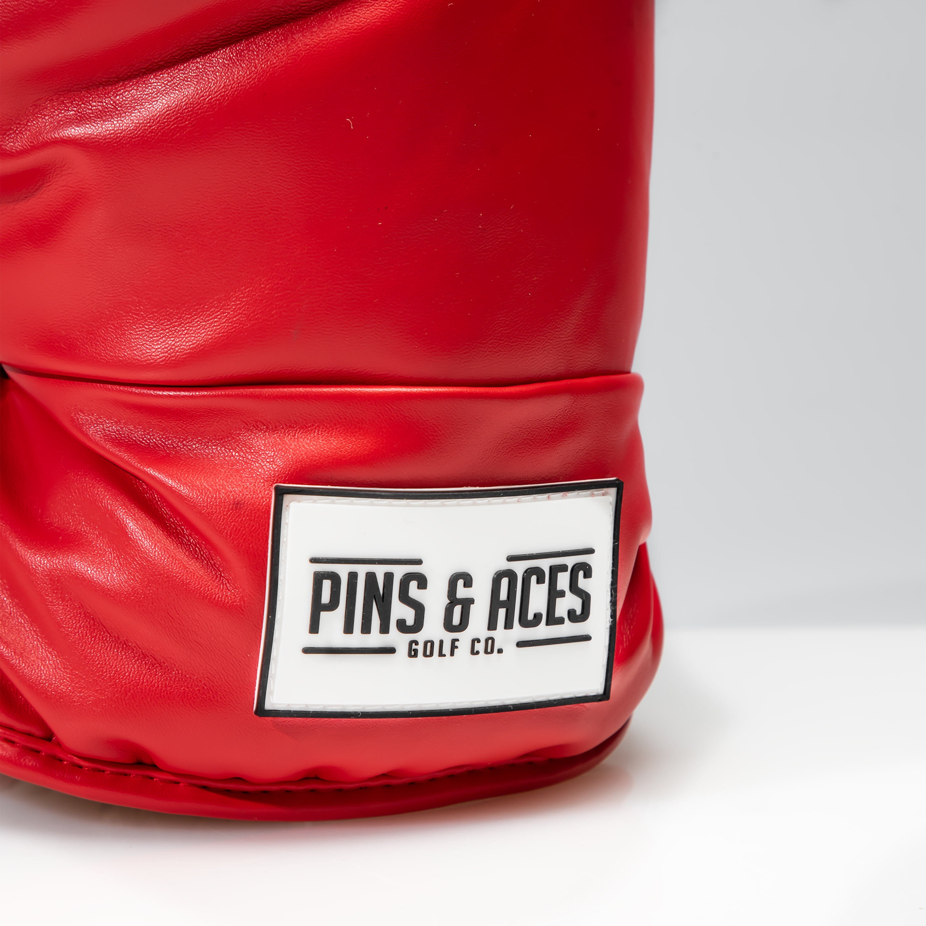 Bold red boxing glove driver cover featuring the Pins & Aces logo, designed for golfers who want to stand out.