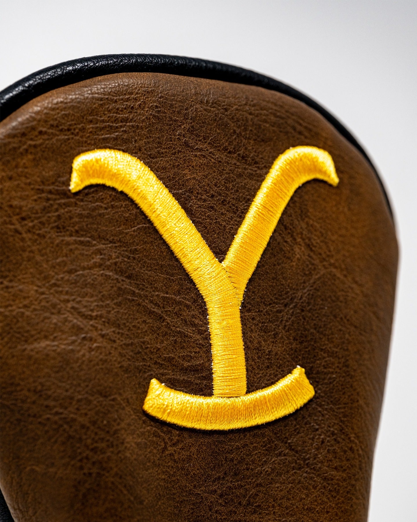 Yellowstone Hybrid Cover featuring a bold yellow embroidered 'Y' on a rich brown leather background.