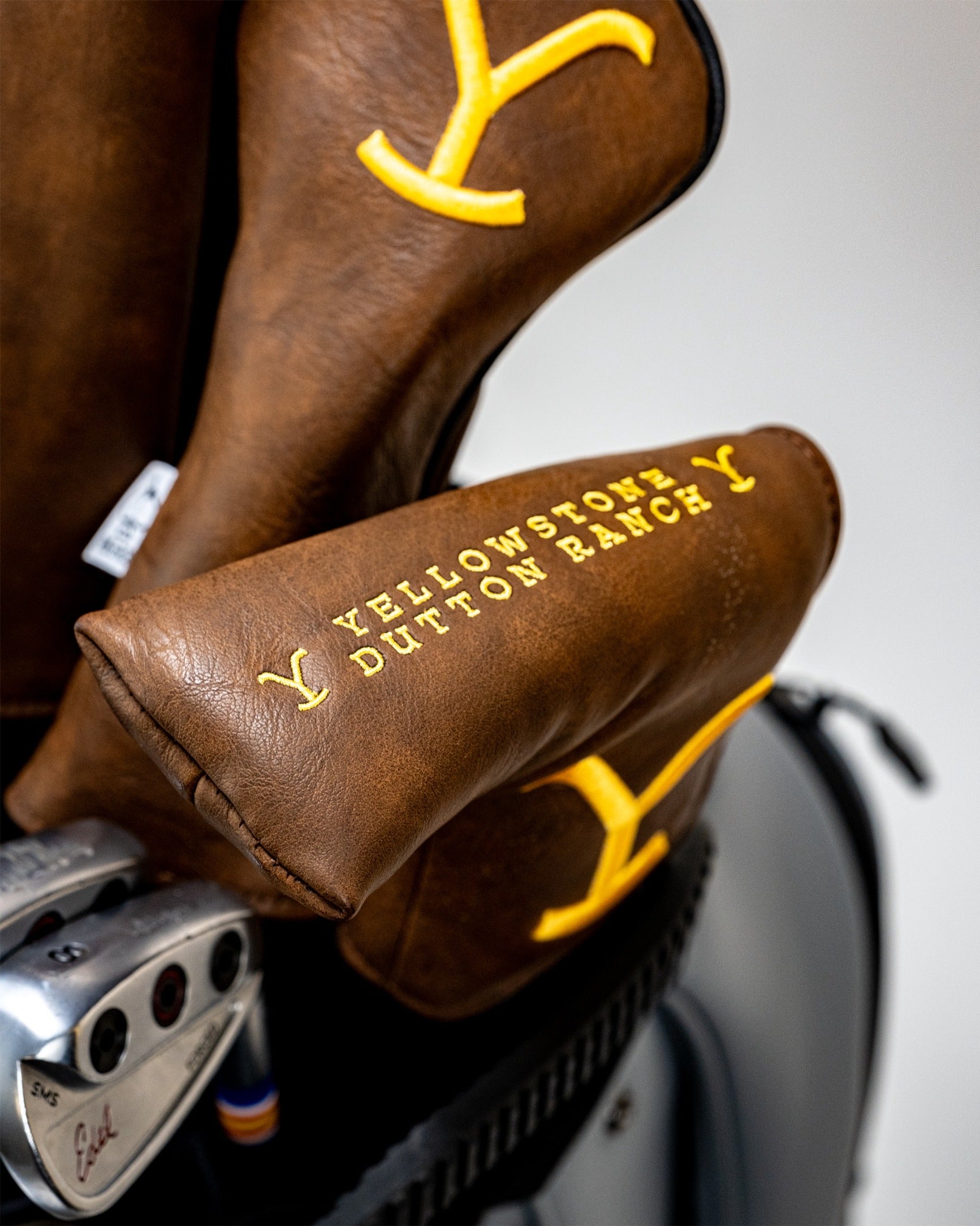 Yellowstone Putter Cover in brown leather featuring yellow lettering and a stylish design for golfers seeking unique accessories.