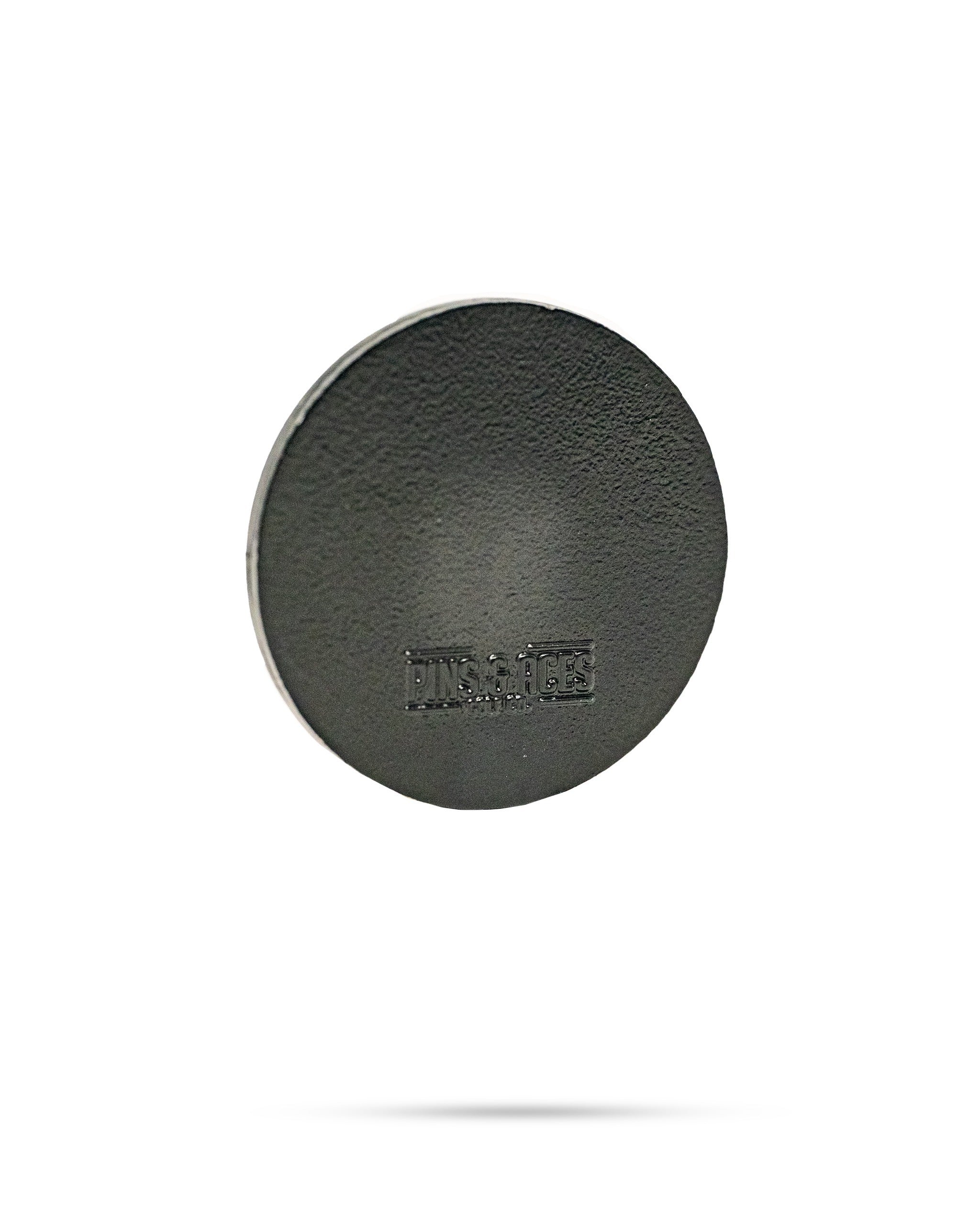 Black 47 ball marker featuring a textured surface and embossed Pins and Aces logo, ideal for golfers seeking style.