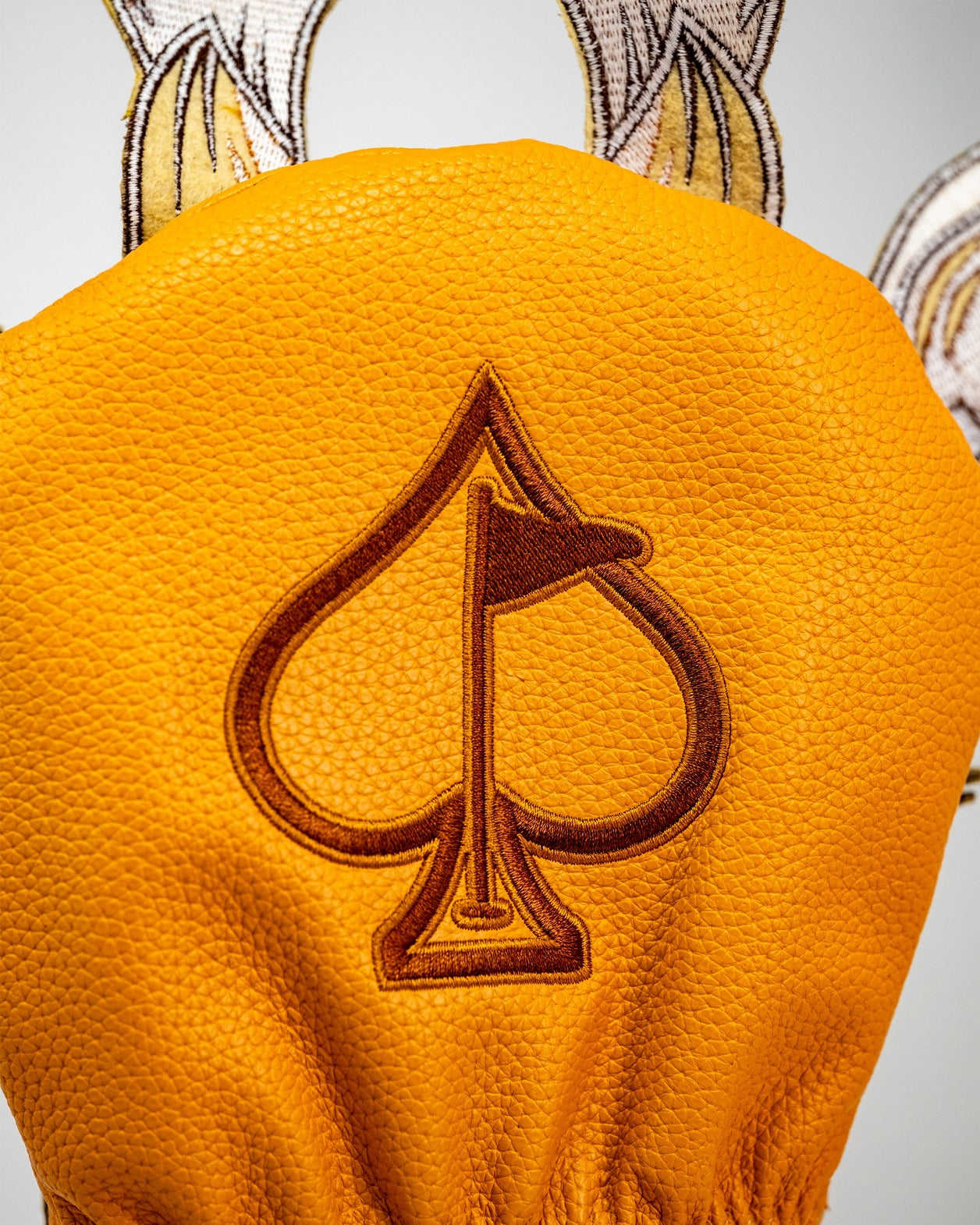 Giraffe driver cover featuring a textured orange design and a brown spade logo, perfect for stylish golfers.