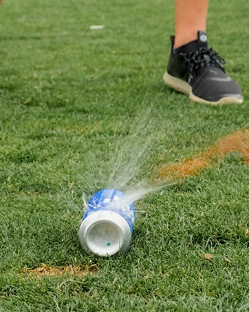 Blue Shottee Golf Tee 3 pack displayed on grass, showcasing a golf ball striking a can, demonstrating impact and fun.