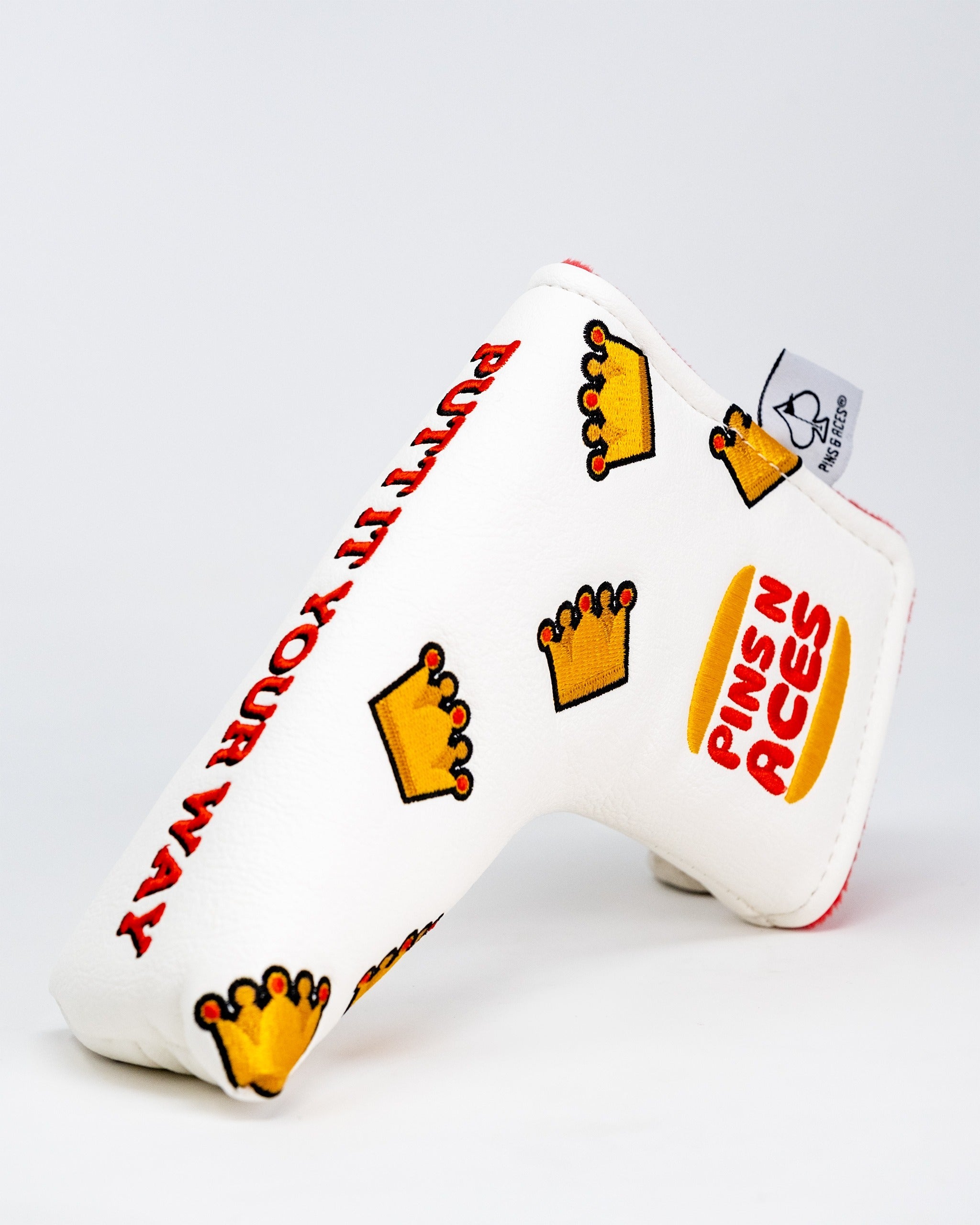 Bold white blade putter cover featuring playful crown designs and "Putt Your Way" text, perfect for standout golfers.