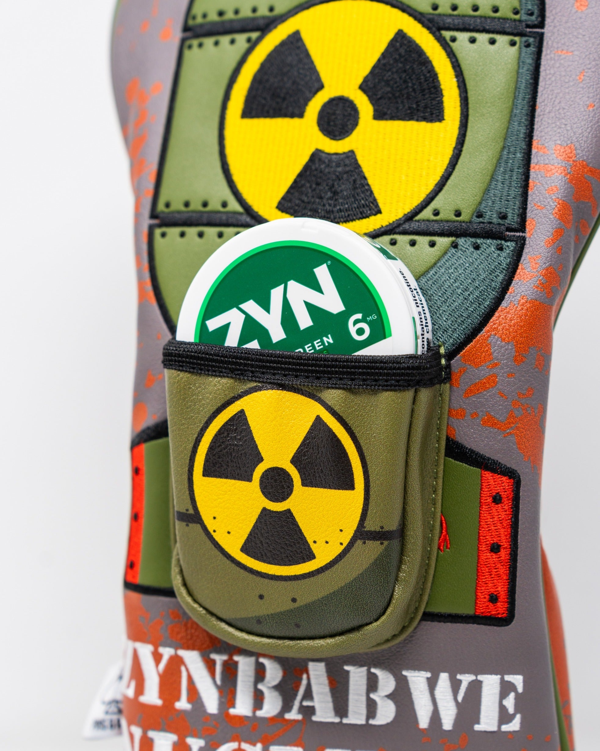 Bold golf driver cover featuring a vibrant design inspired by nuclear themes, with a pocket for ZYN nicotine pouches.