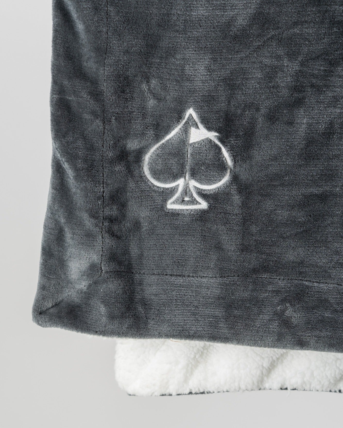 Cozy dark gray Bogey Blanket featuring a soft white underside and embroidered spade logo, perfect for golfers.