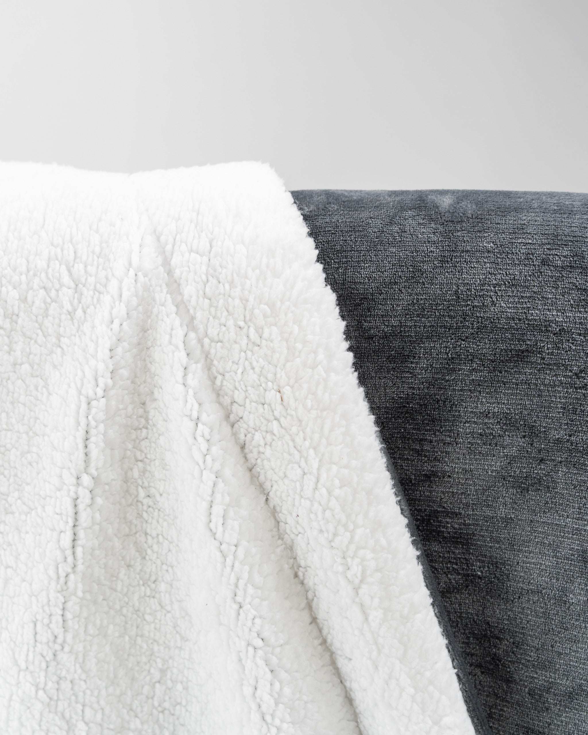 Cozy dark gray Bogey Blanket featuring a soft, plush texture with a contrasting white fleece side. Perfect for warmth on the course.