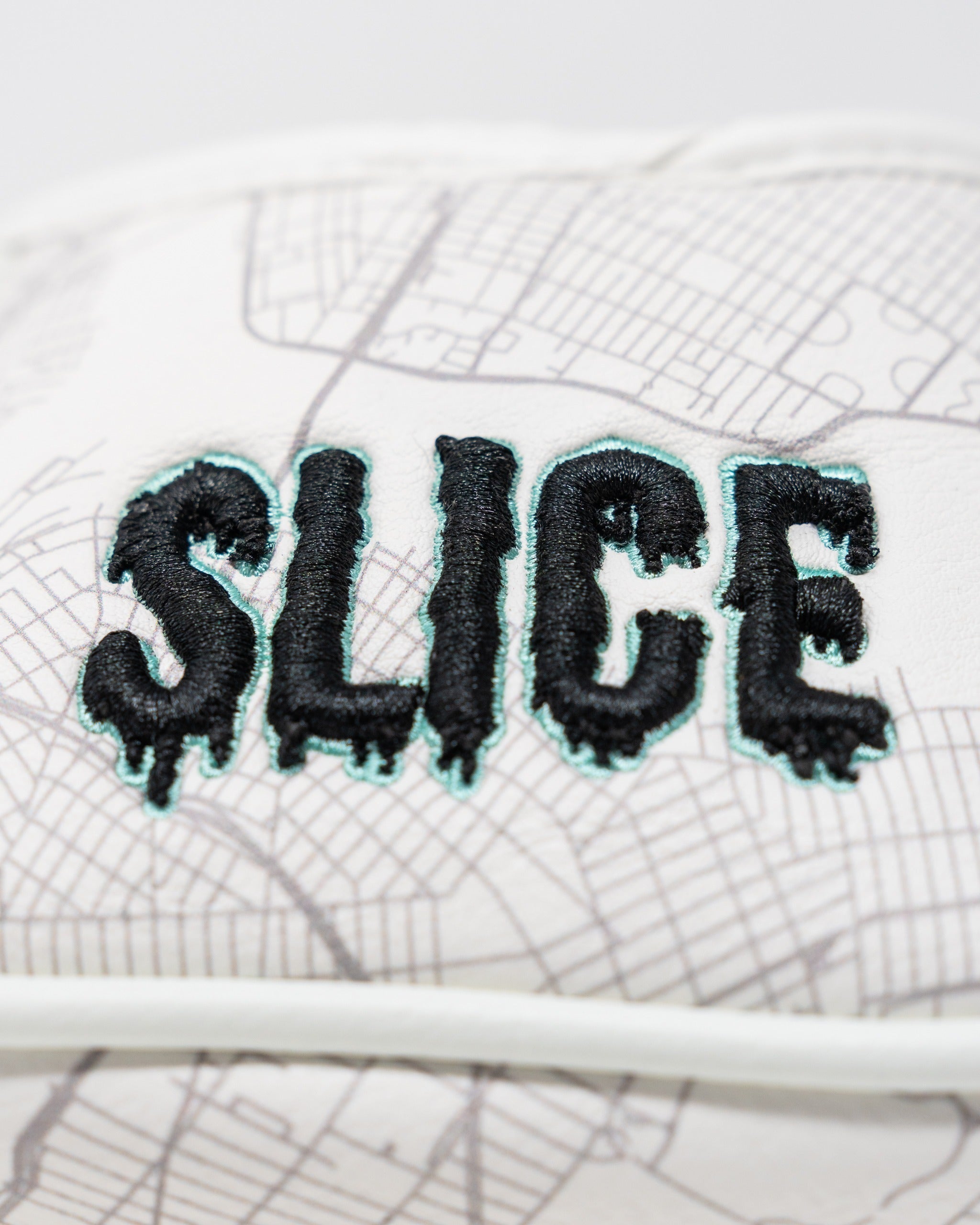 Bold mallet putter cover featuring the word "SLICE" in a striking black and turquoise design on a map background.