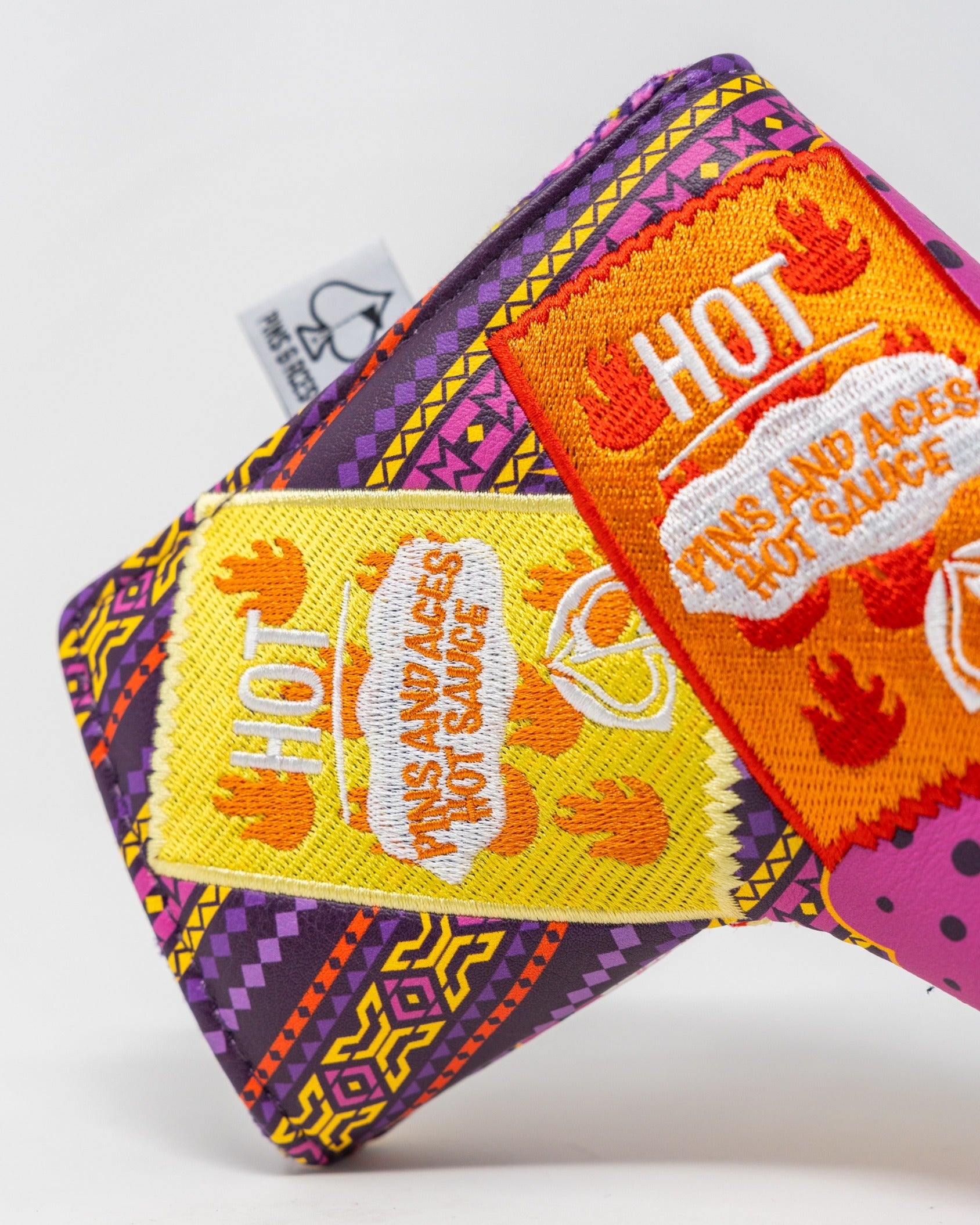 Bold blade putter cover featuring vibrant patterns and playful hot sauce graphics for a standout golf accessory.