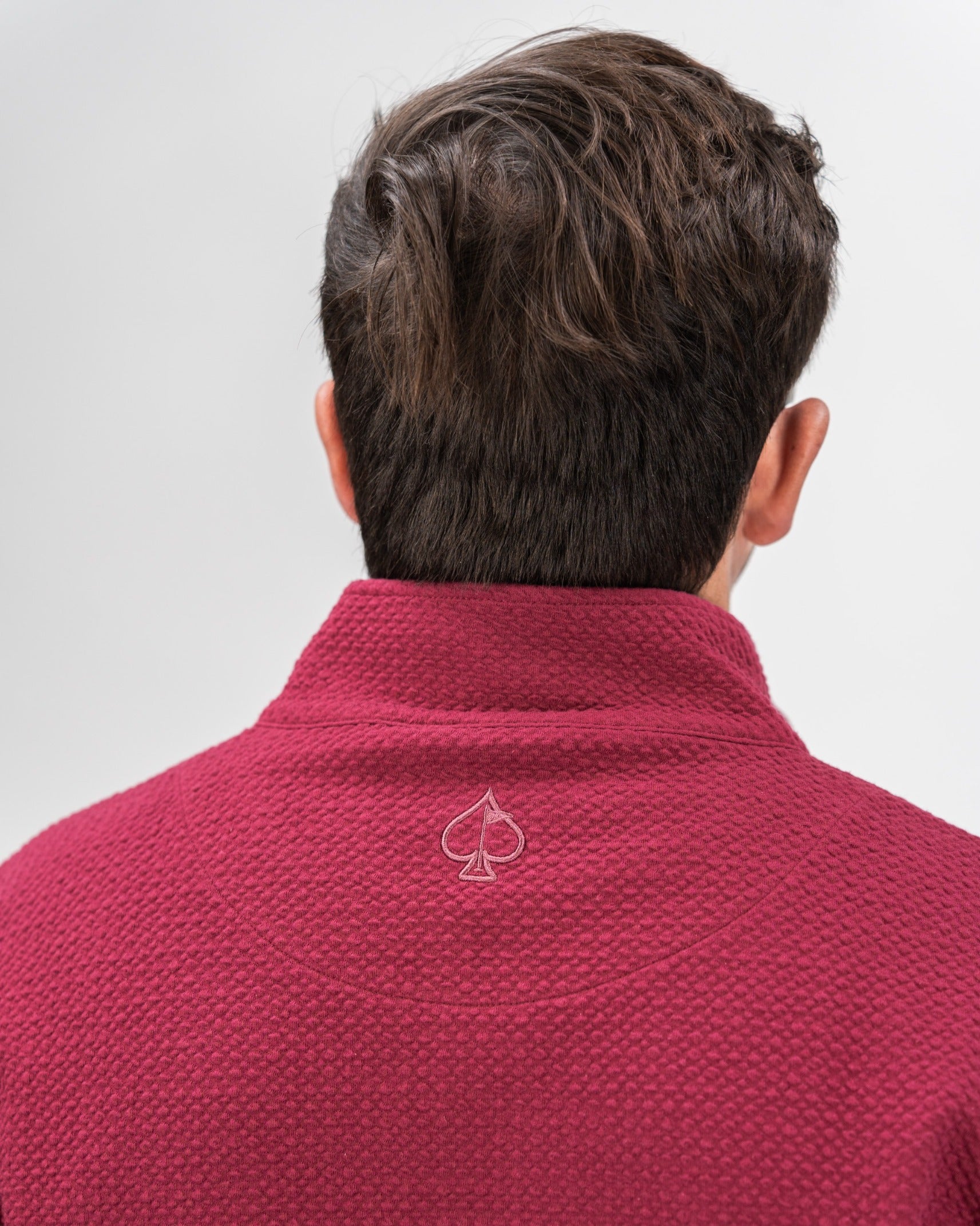 Back view of a man wearing a merlot Player Preferred waffle knit pullover, featuring a subtle logo at the collar.