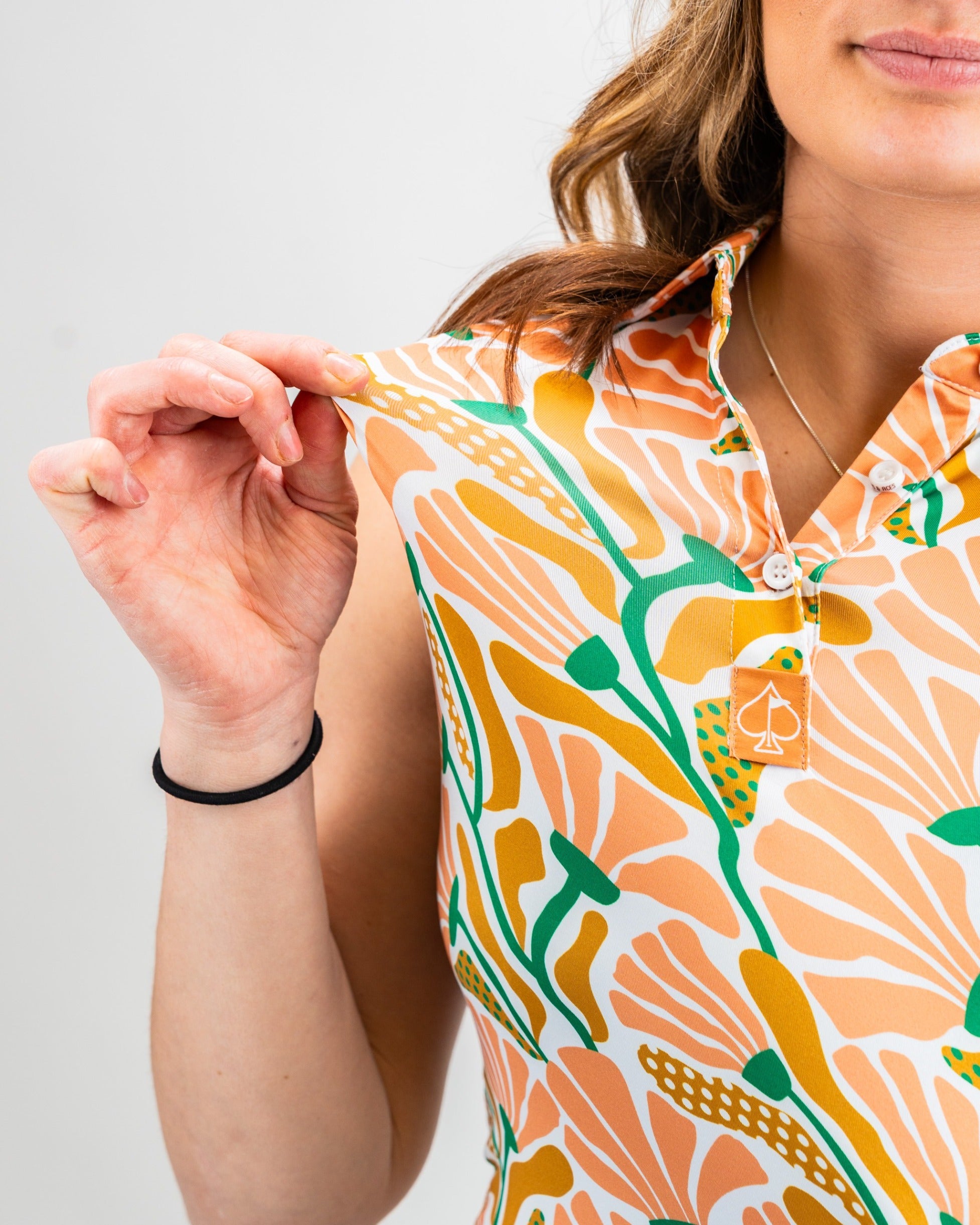 Close-up of a woman holding the collar of a colorful floral-patterned sleeveless shirt from the Women's Garden Party Spritz collection.