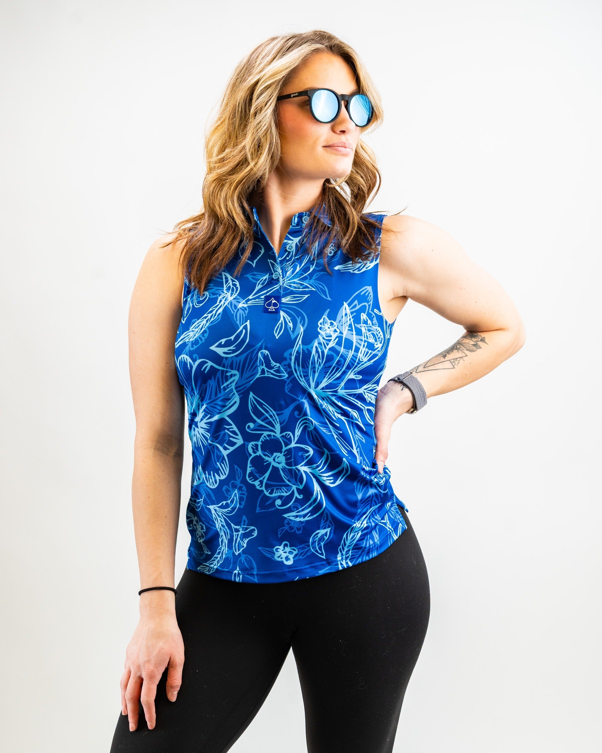 Stylish women's sleeveless golf top in vibrant blue with floral patterns, perfect for a bold look on the course.