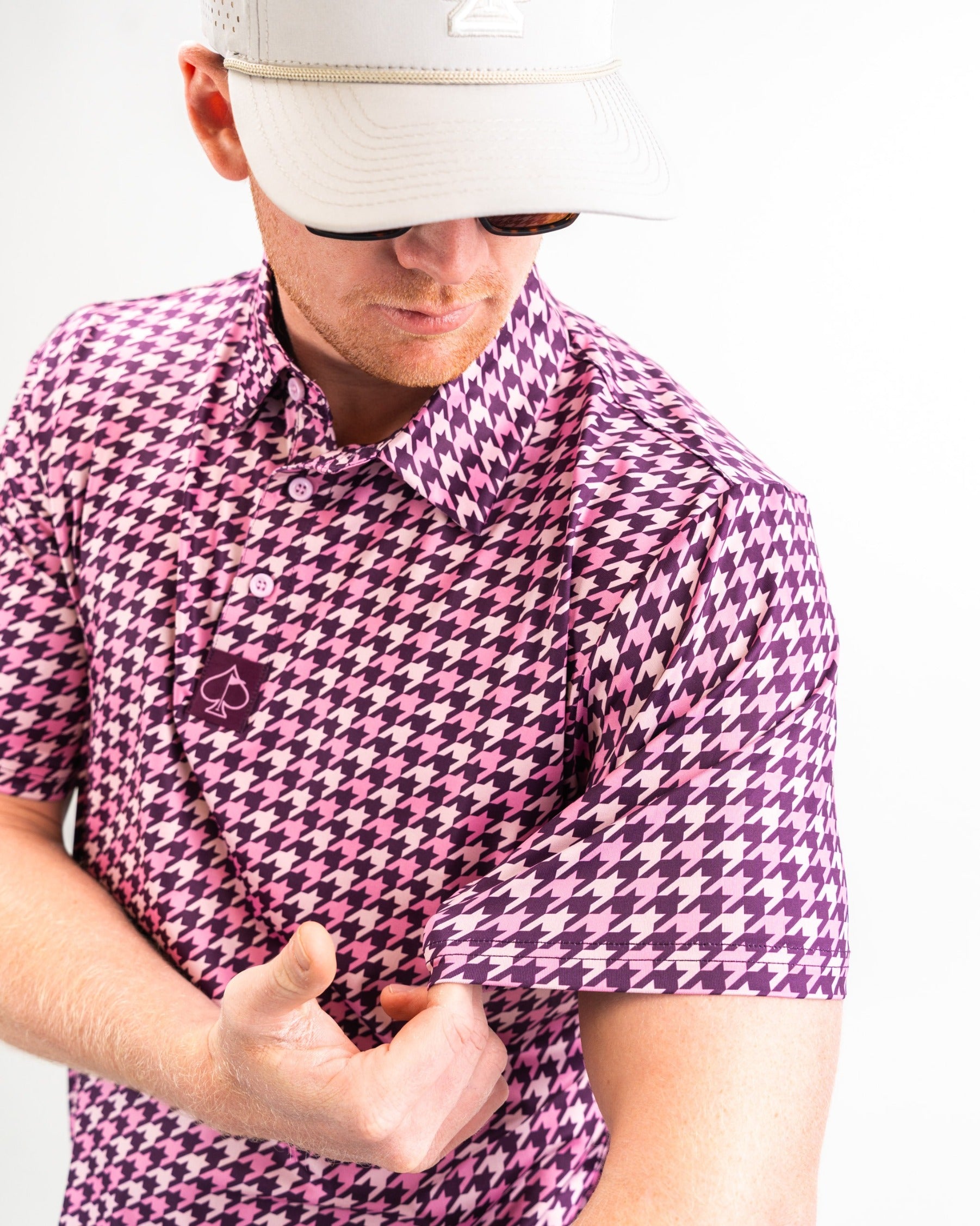 Bold houndstooth golf shirt in raspberry and purple, featuring a stylish collar and short sleeves for a standout look on the course.