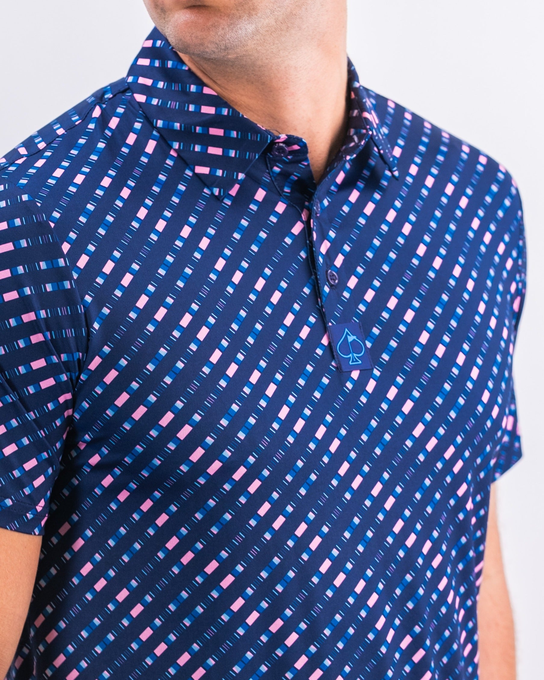 Chromo Blue golf polo featuring a bold geometric pattern in blue and pink, designed for stylish performance on the course.