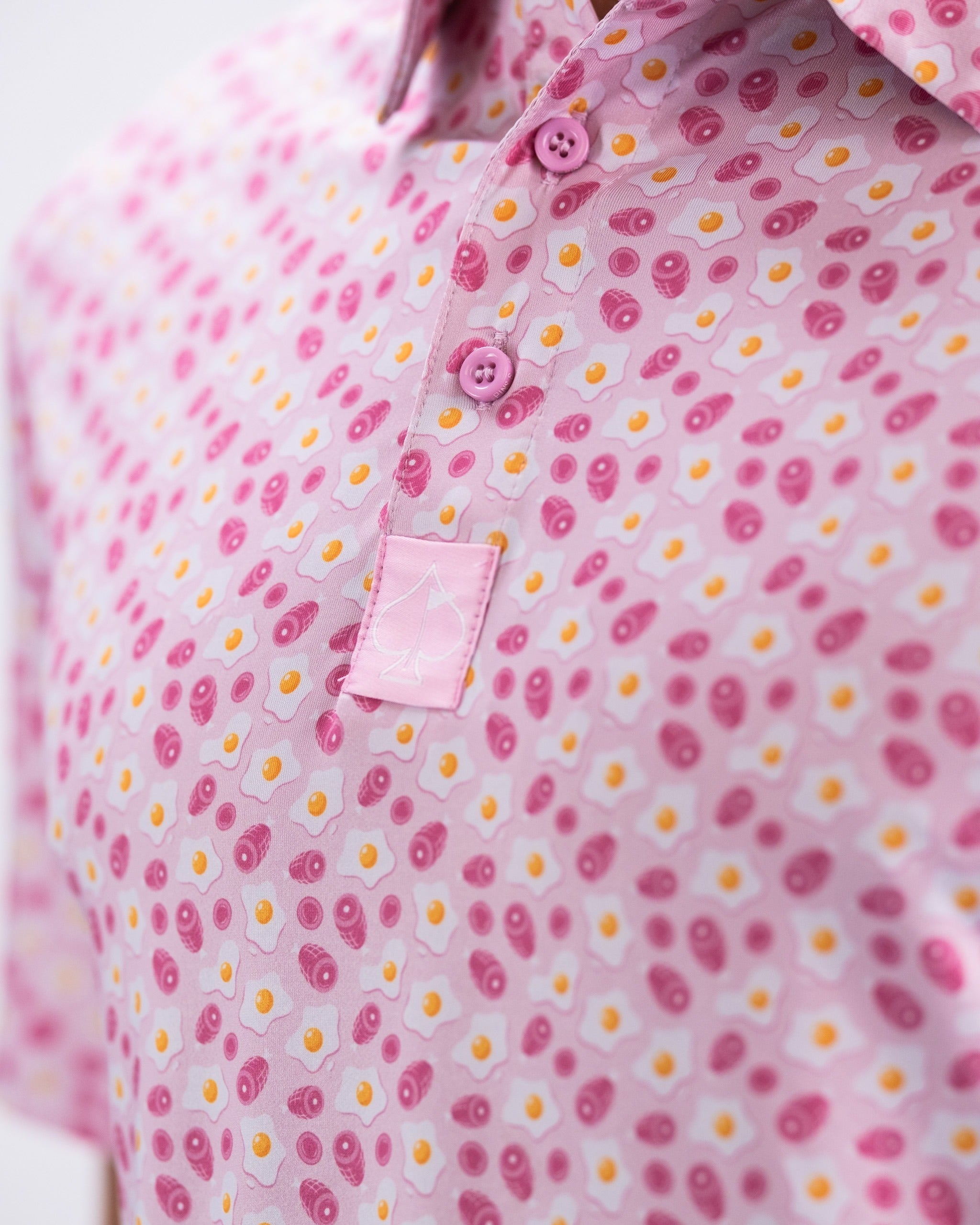 Bold pink golf polo featuring a playful ham and egg pattern, designed for golfers who want to stand out on the course.