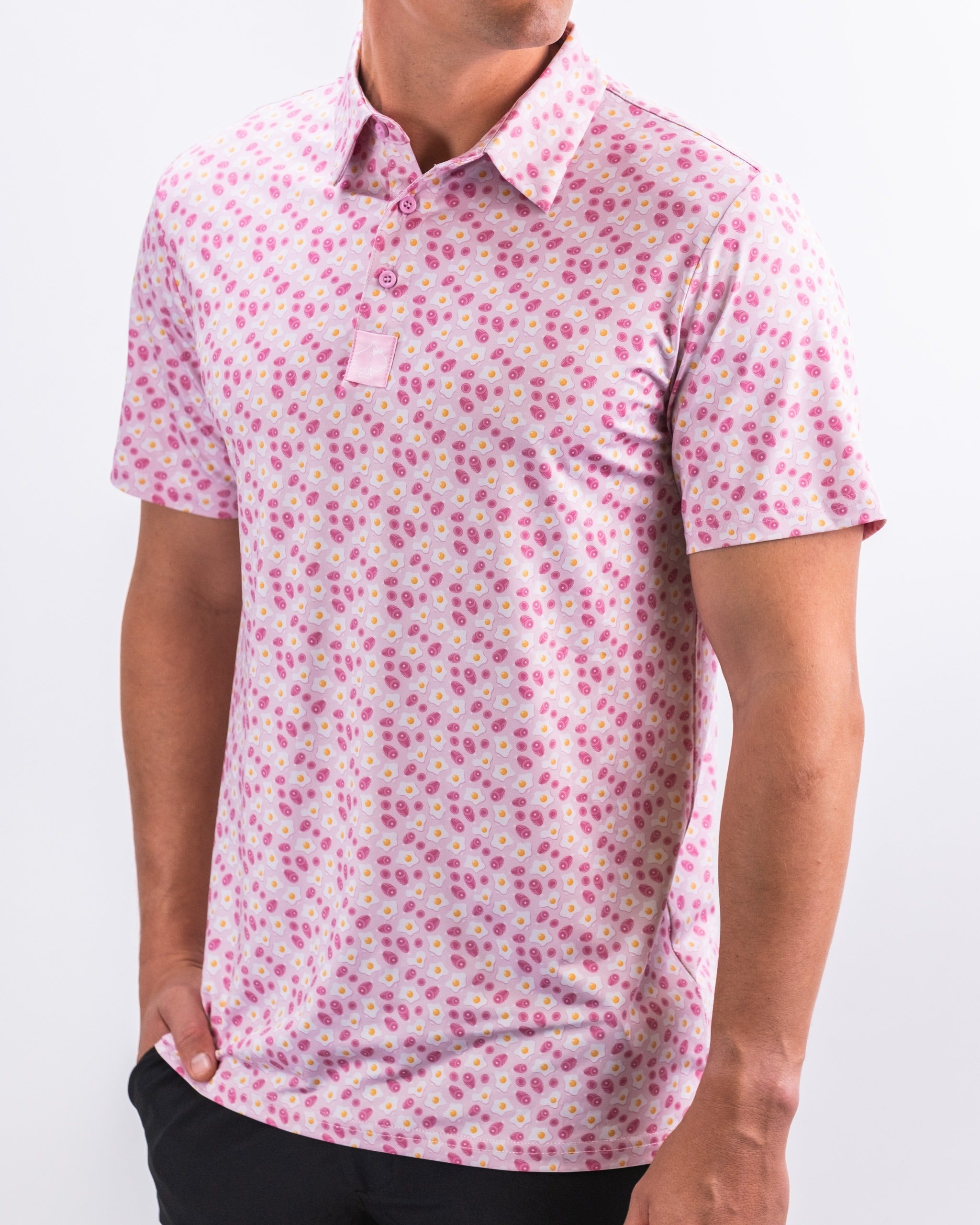 Men's short-sleeve golf shirt in pink with a playful ham and egg pattern, designed for a bold, stylish look on the course.