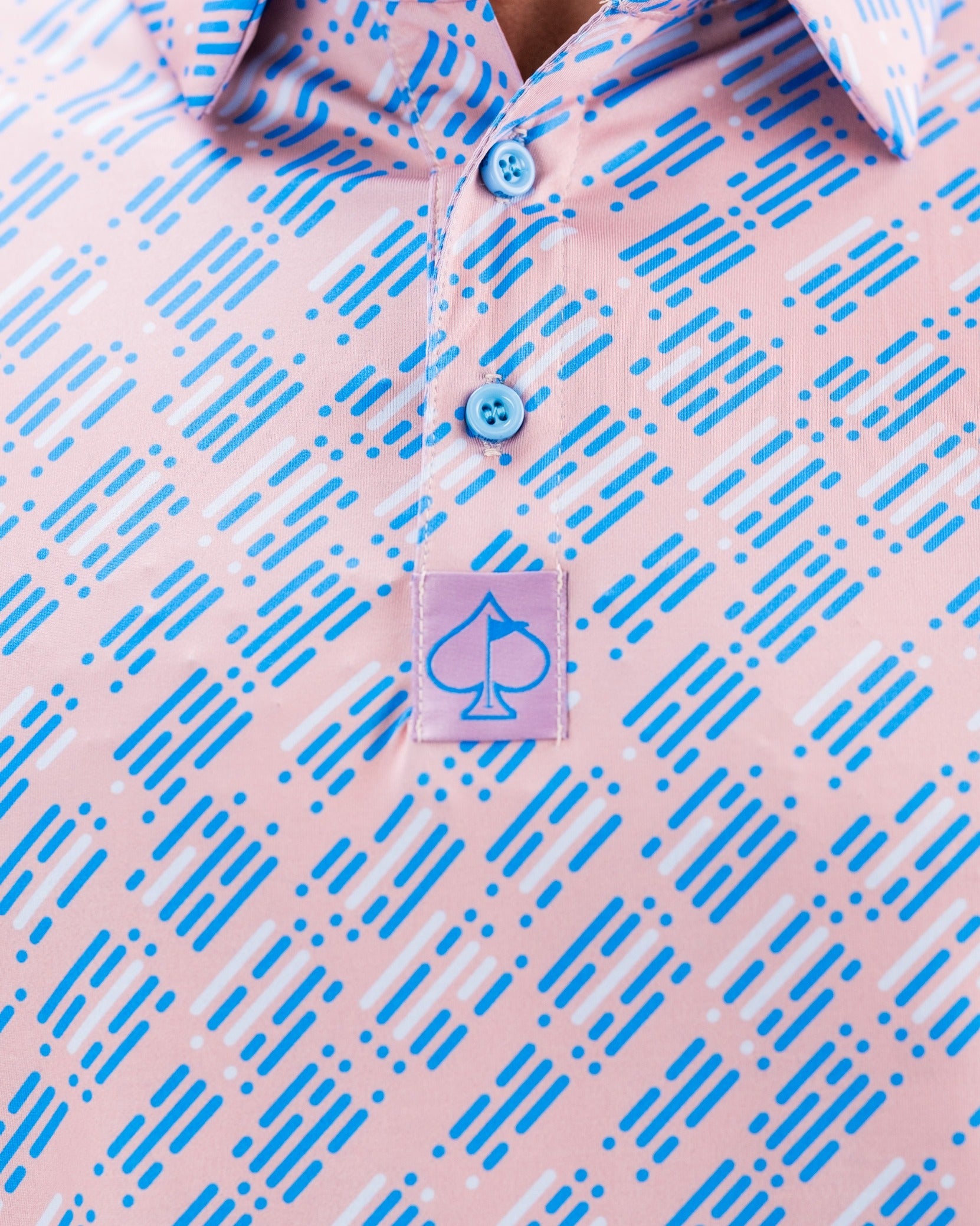 Bold pink golf shirt featuring a geometric pattern in blue, with a logo patch on the chest for a stylish look on the course.