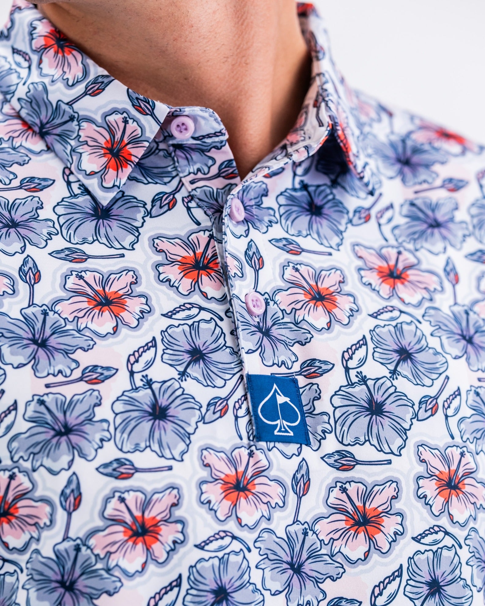 Colorful Hibiscus Harmony golf shirt featuring a vibrant floral pattern and a logo on the collar, perfect for stylish golfers.