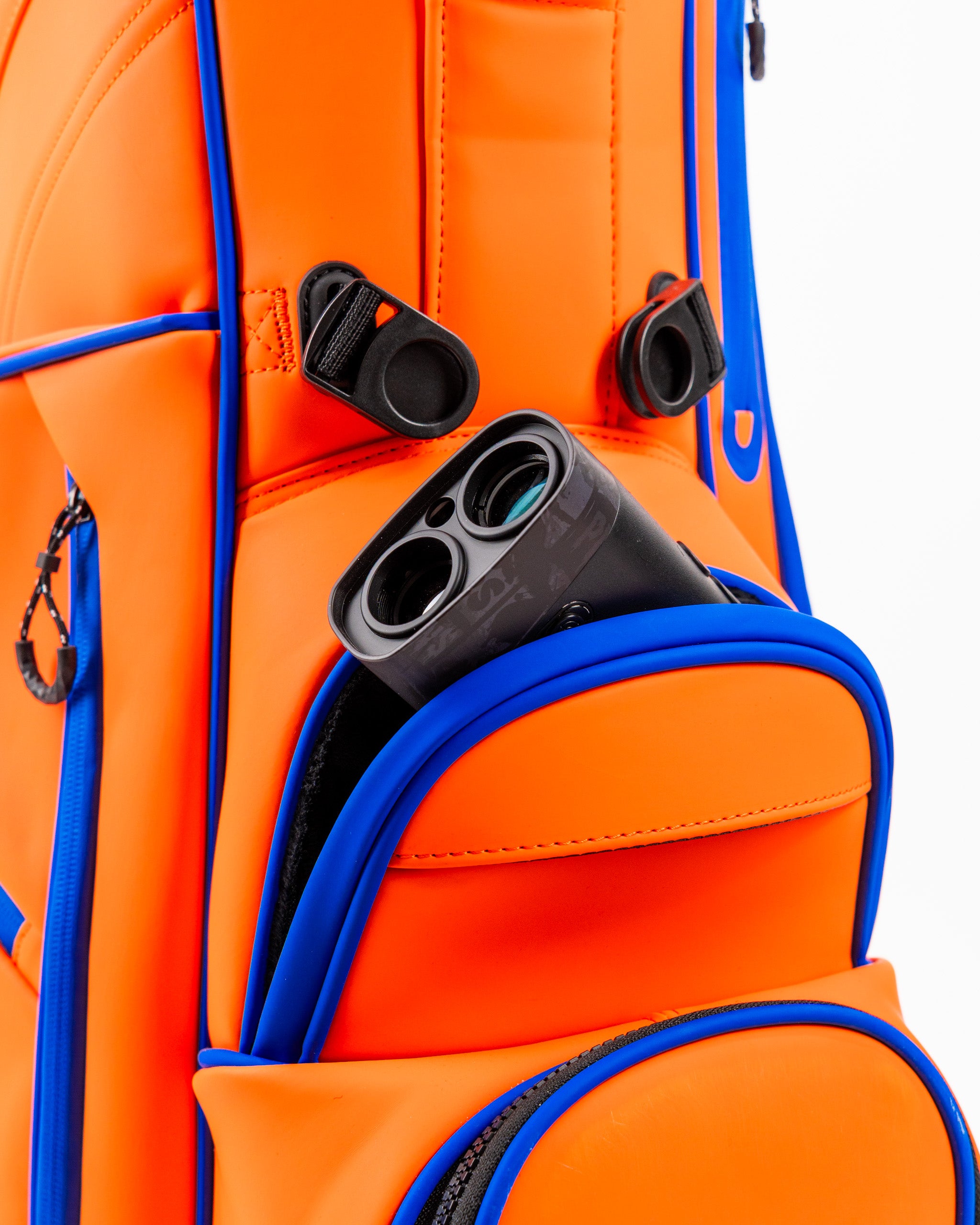Bright orange golf bag with blue accents, featuring a pocket holding a golf rangefinder.