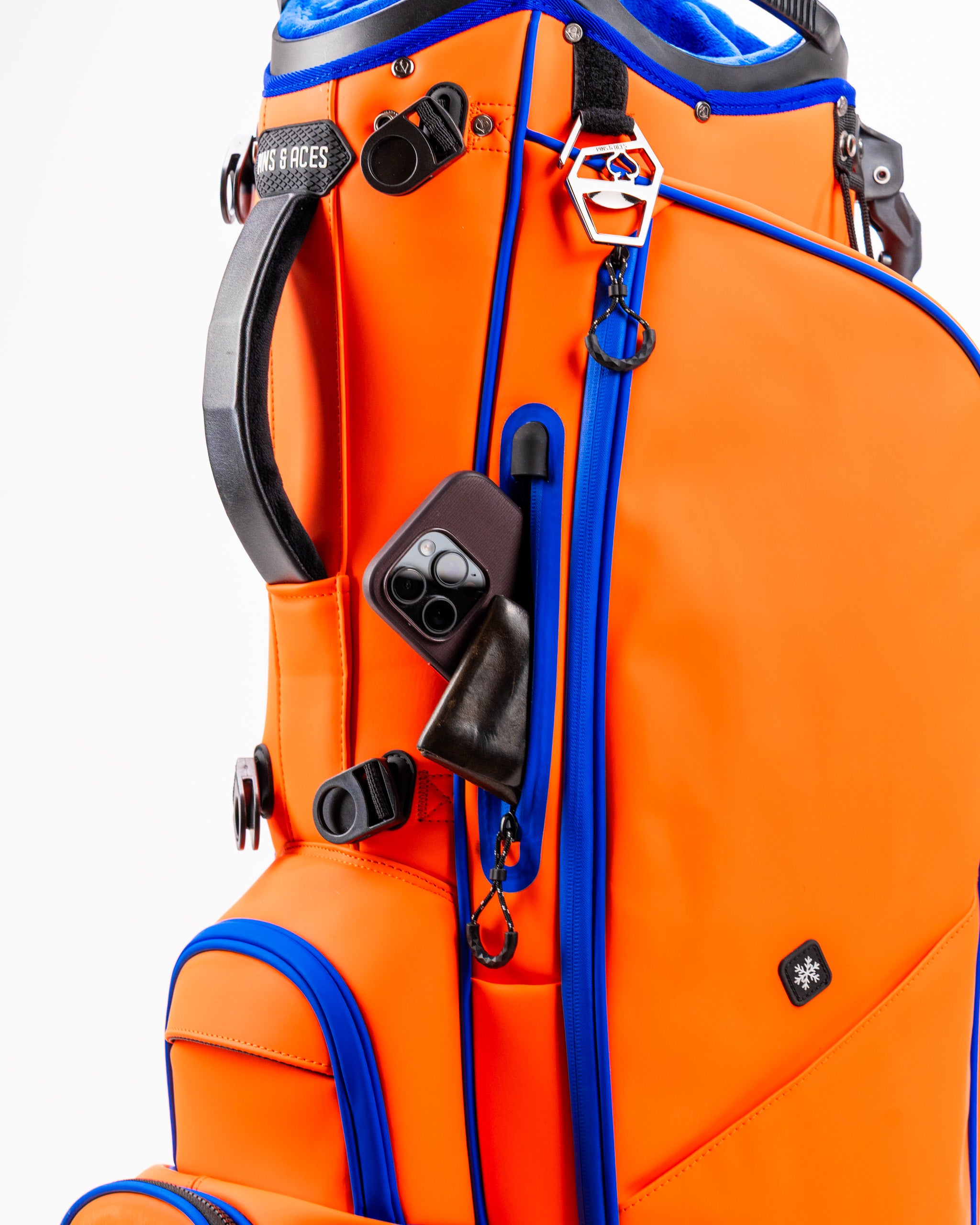 Bright orange golf bag with blue accents, featuring multiple pockets and a sleek design for stylish golfers.