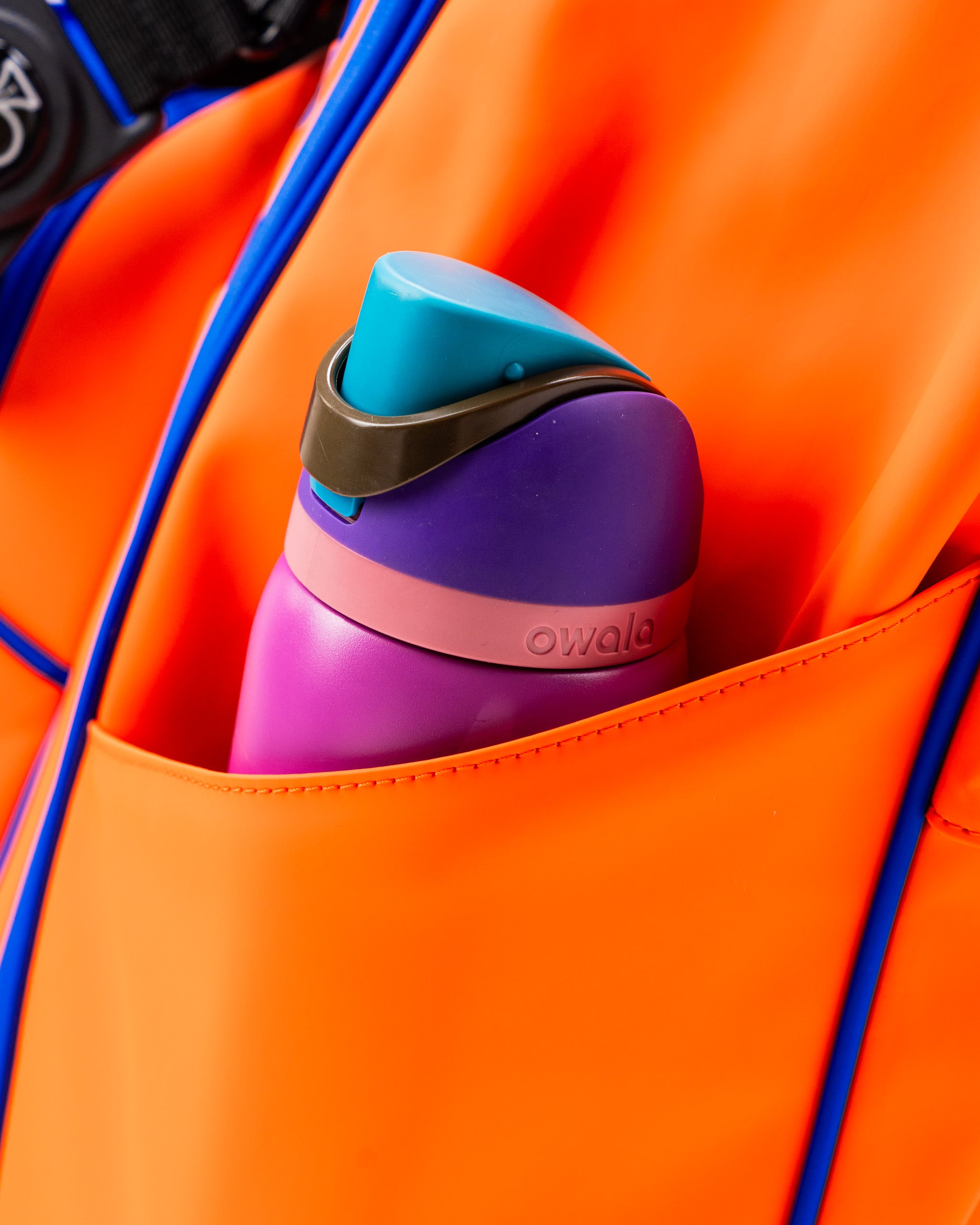 Bright orange golf bag featuring a pocket with a colorful water bottle, designed for stylish and functional use on the course.
