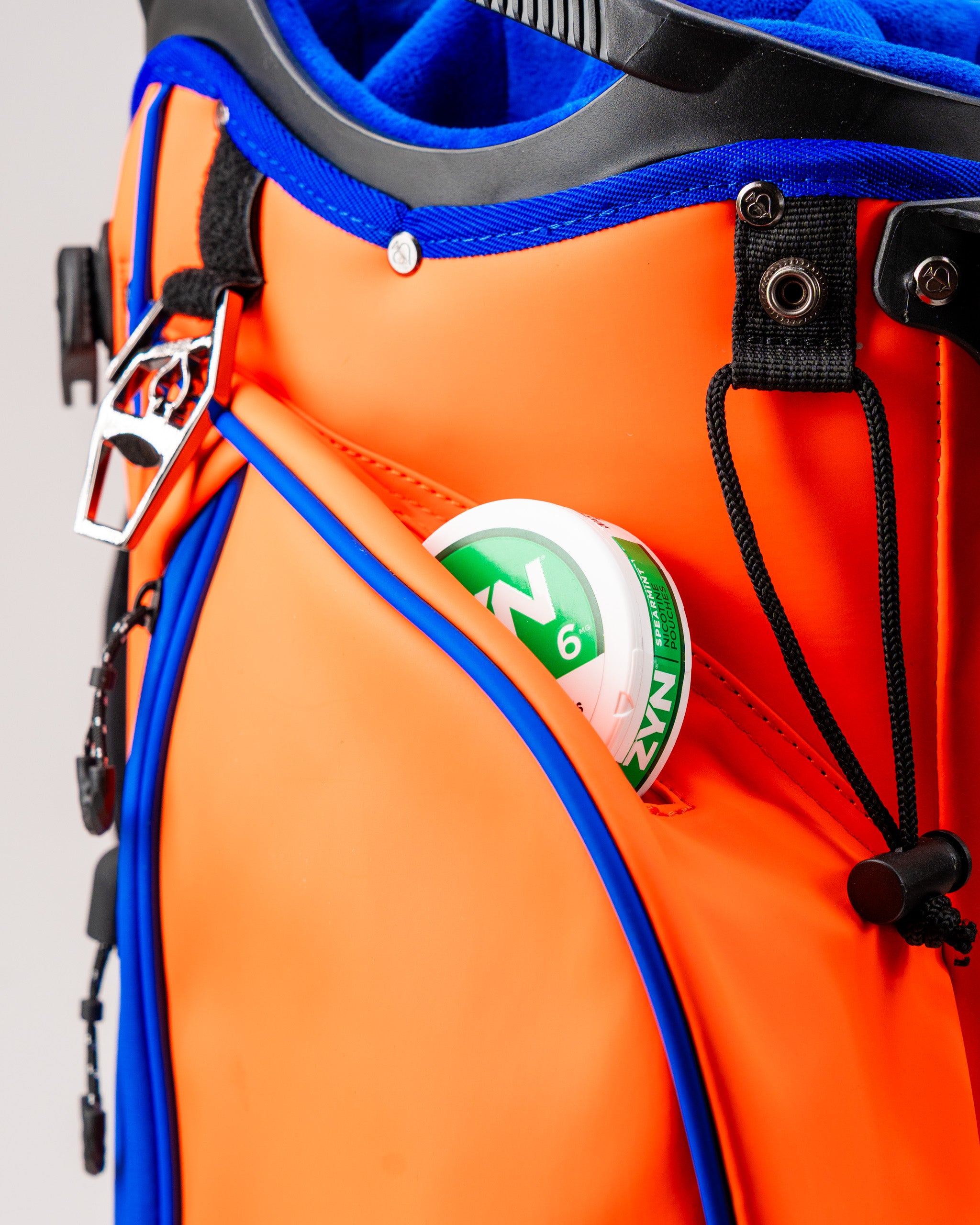 Orange Crush Player Preferred golf bag featuring a side pocket with a golf ball peeking out, showcasing its vibrant design.