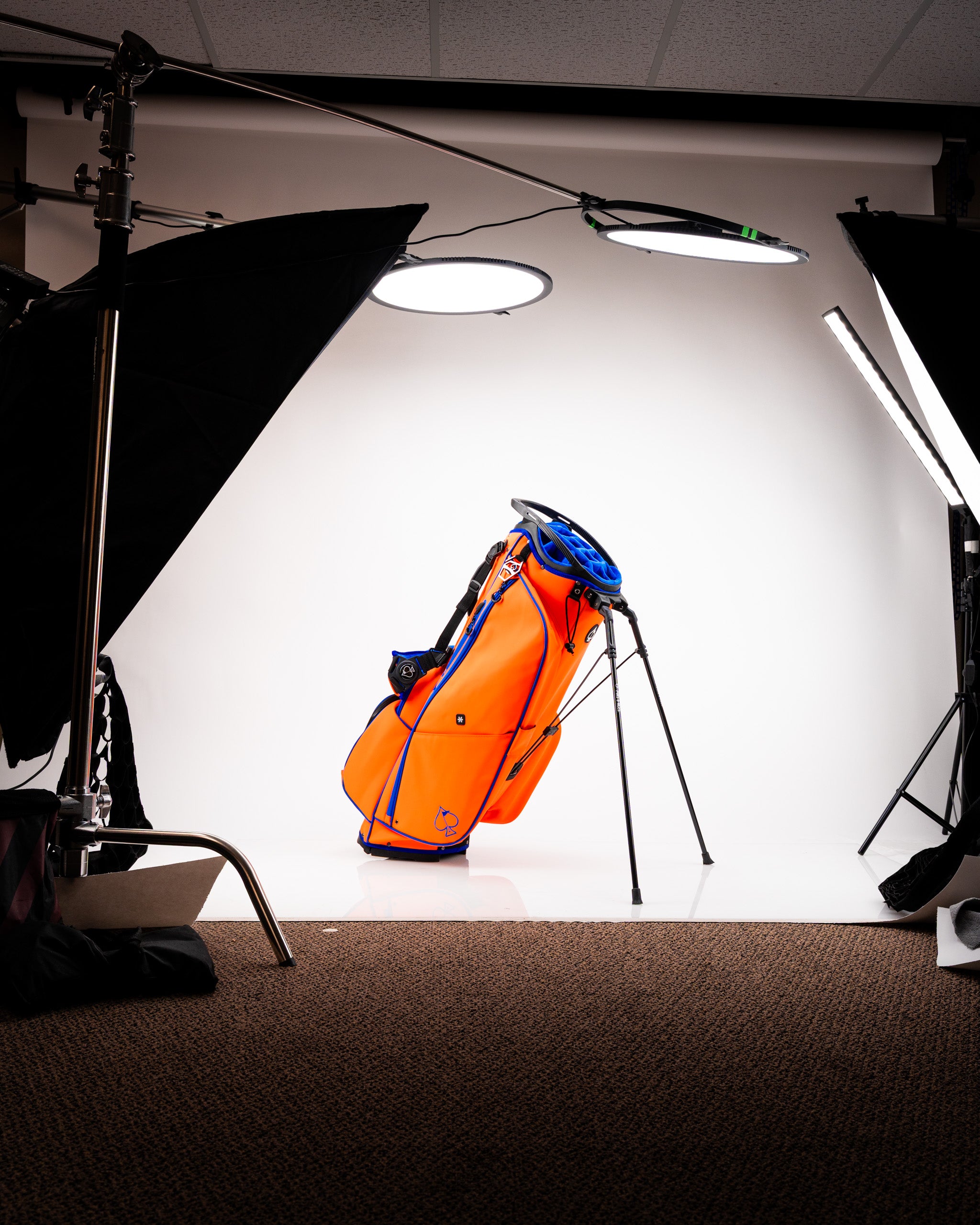 Bold orange golf bag with blue accents, featuring a stand and sleek design, perfect for stylish golfers on the course.