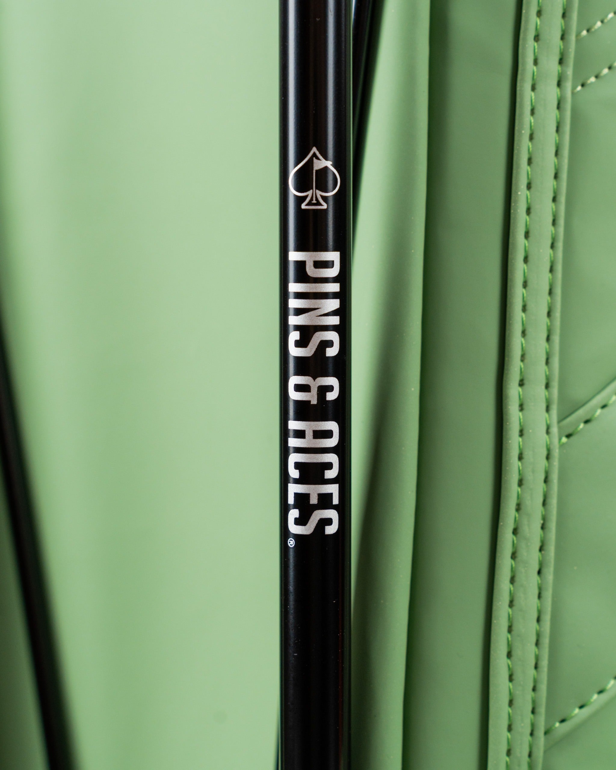 Close-up of the Player Preferred Golf Bag in sage green, featuring the Pins & Aces logo on a black club shaft.